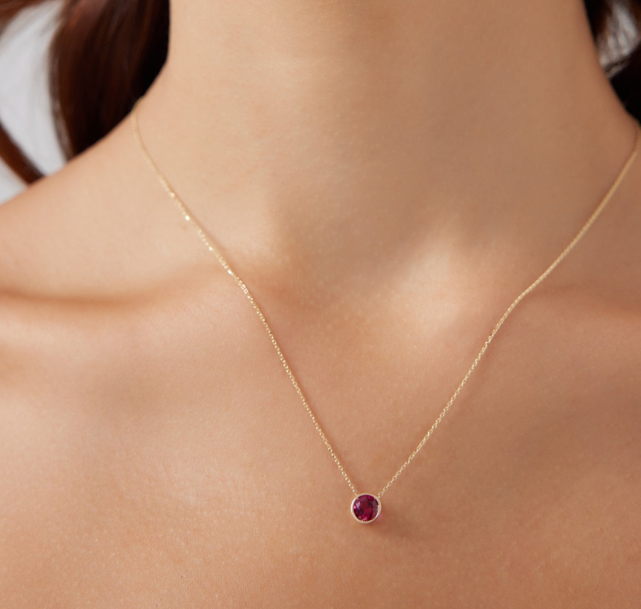 14K white gold bezel set ruby solitaire necklace showcased on a model, featuring a 6mm ruby pendant.