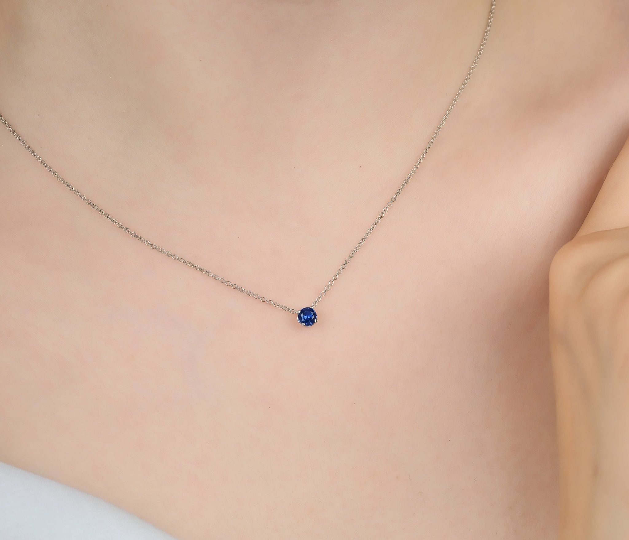 Dainty 14K white gold minimalist 5mm prong setting sapphire solitaire necklace worn on neck.