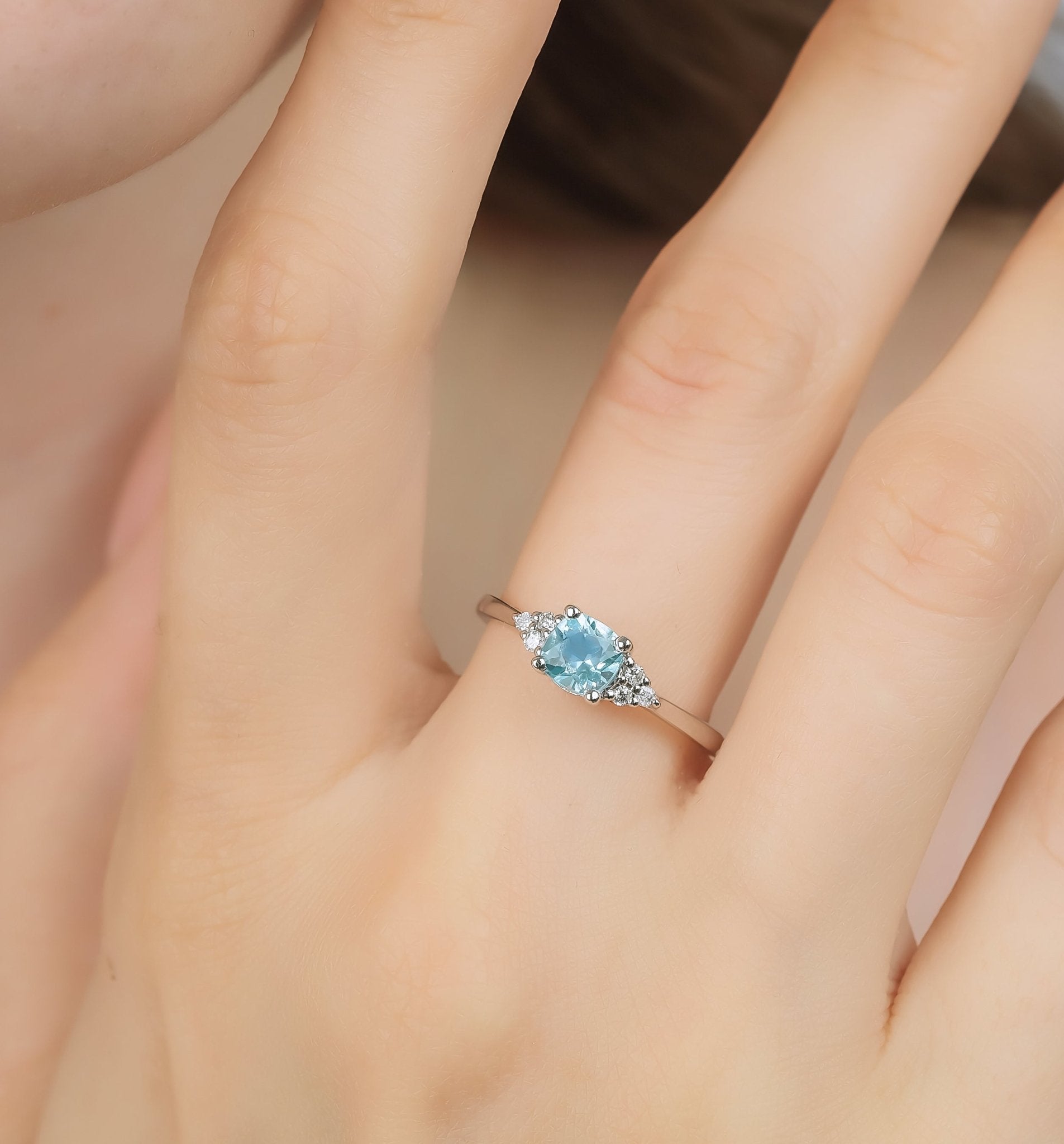 14K white gold women's cushion cut aquamarine ring with diamond accents worn on a hand.