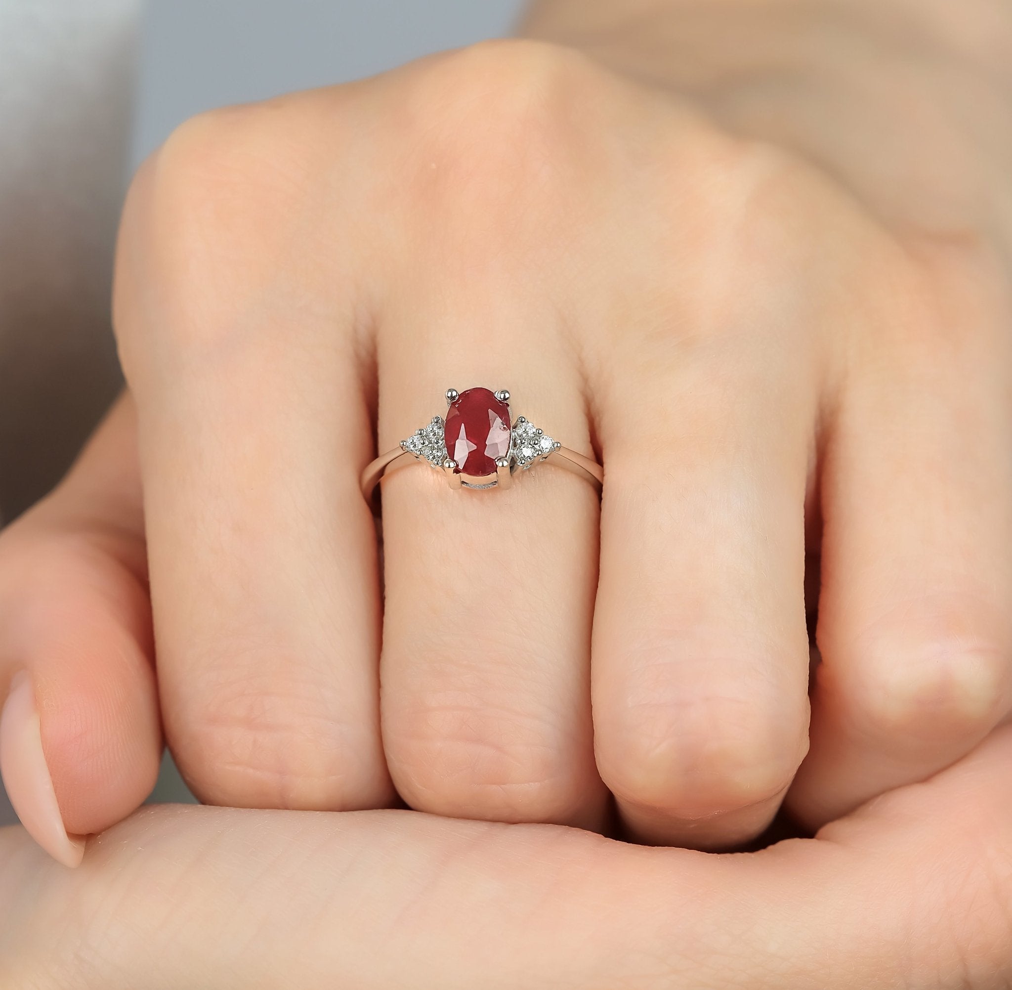 14K white gold women's oval ruby and diamond ring worn on hand, showcasing a 1 carat ruby and 6 round diamonds.