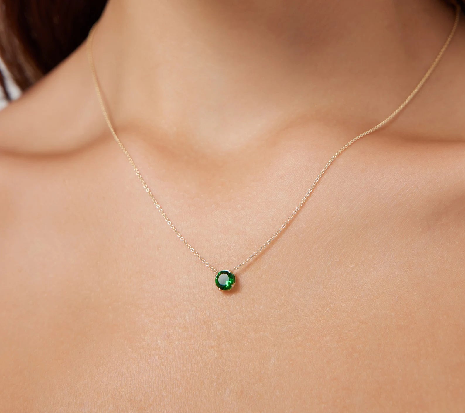 14K yellow gold minimalist 5mm prong setting emerald necklace worn on neck, featuring a delicate and dainty design.