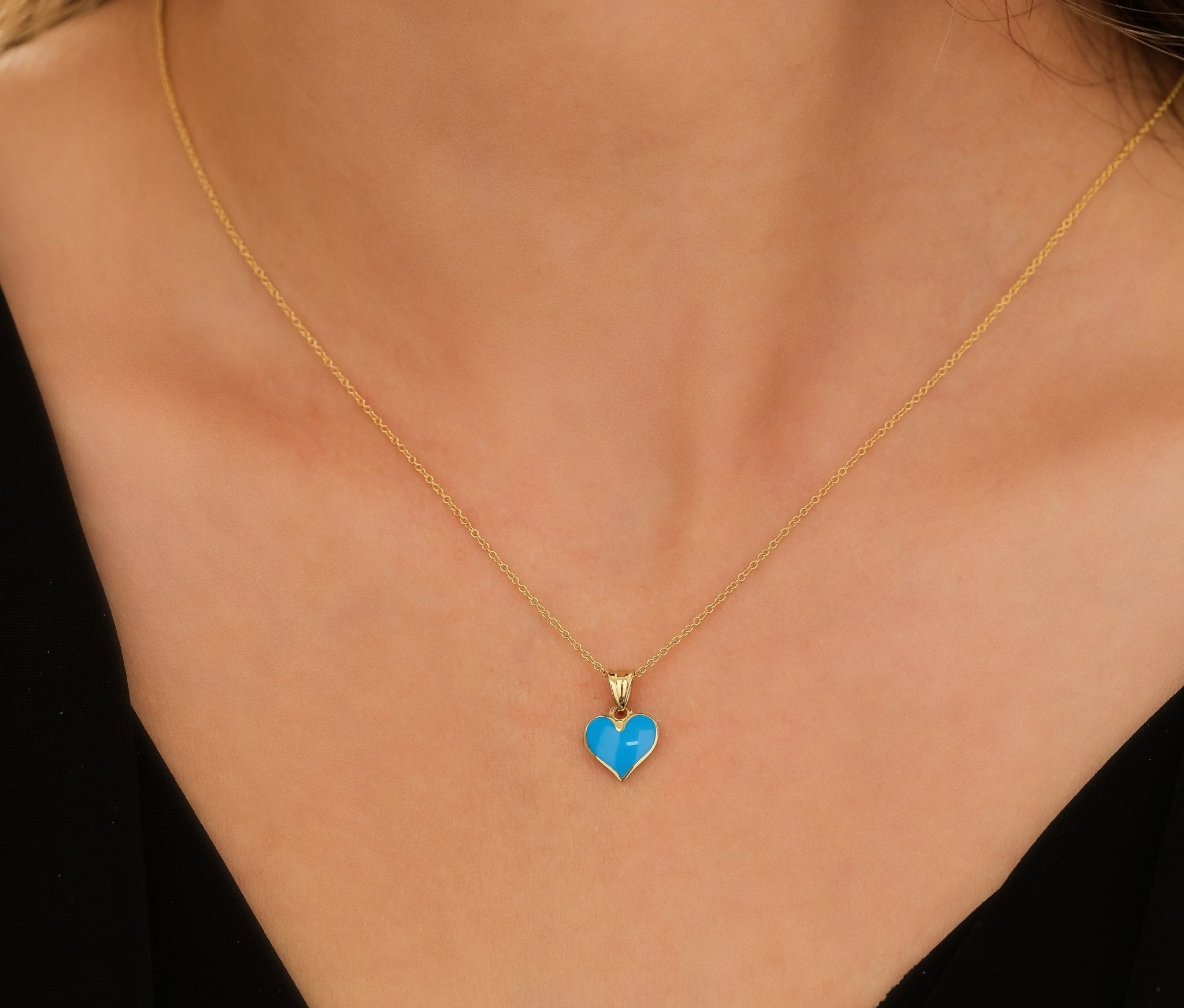 14K yellow gold blue enamel heart necklace worn on a model's neck, showcasing its elegant design and vibrant color.
