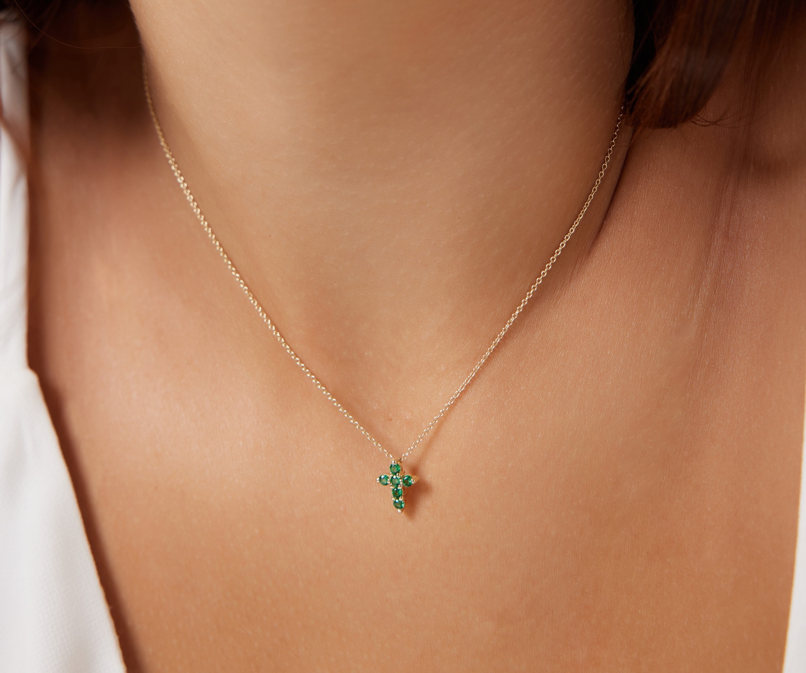 14K solid yellow gold minimalist Emerald cross necklace elegantly worn, featuring 6 lab-created emerald stones.