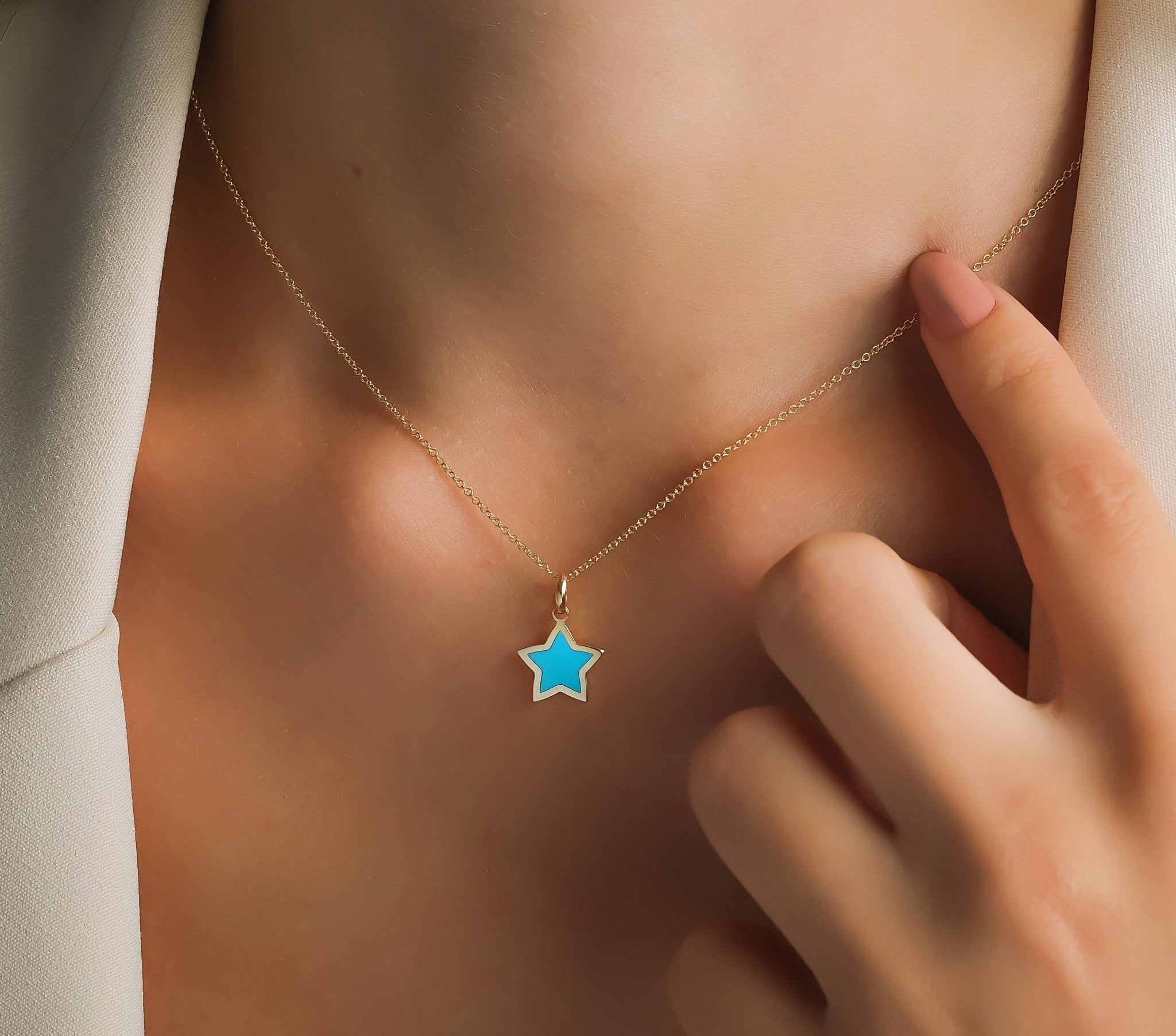 Dainty 14K yellow gold necklace featuring a minimalist turquoise star pendant on a model's neck.