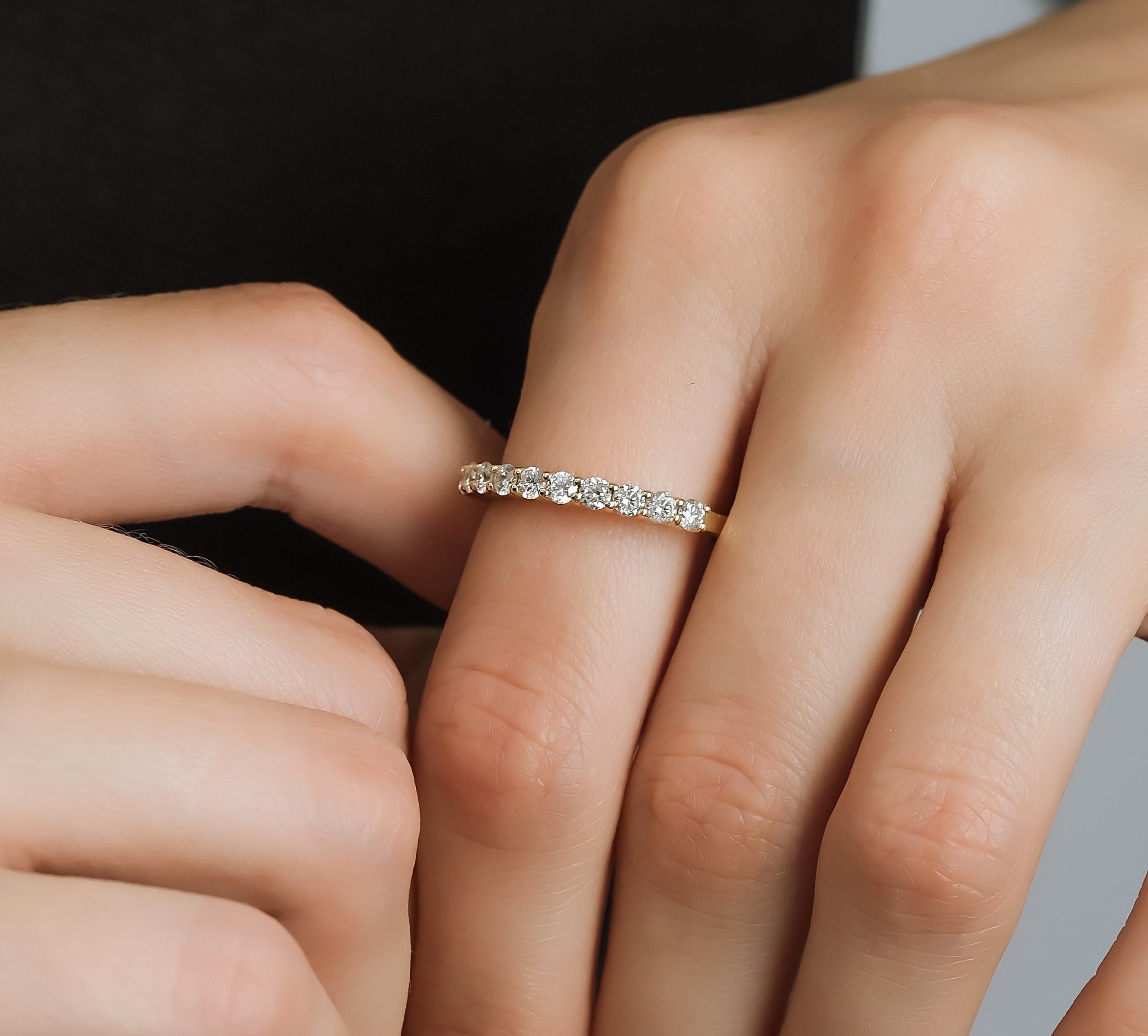 14K yellow gold half eternity diamond wedding ring with 11 round diamonds, showcasing a shiny finish on a model's hand.
