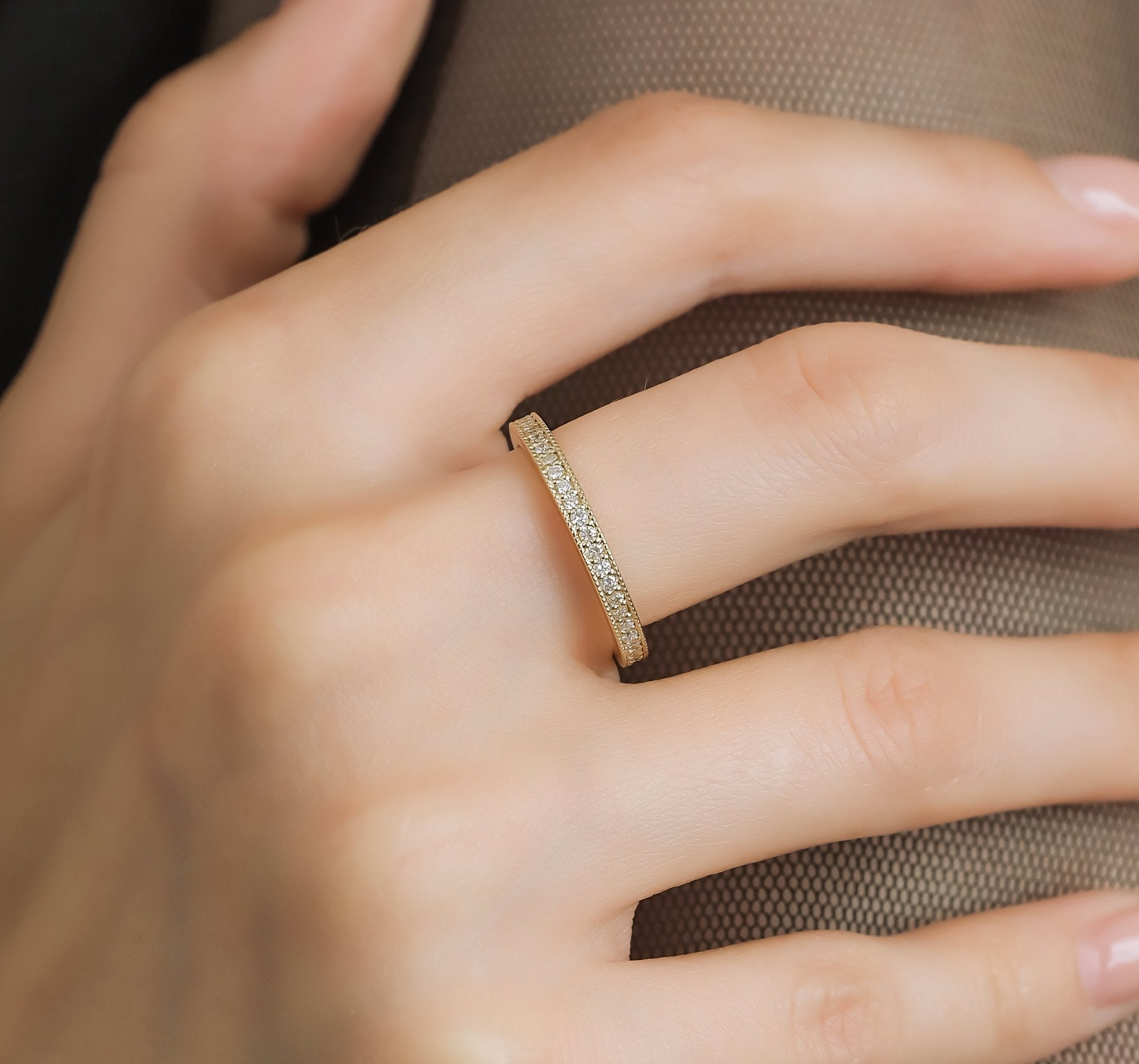14K yellow gold full eternity diamond wedding band on a hand, sparkling diamonds in shiny finish, elegant design.