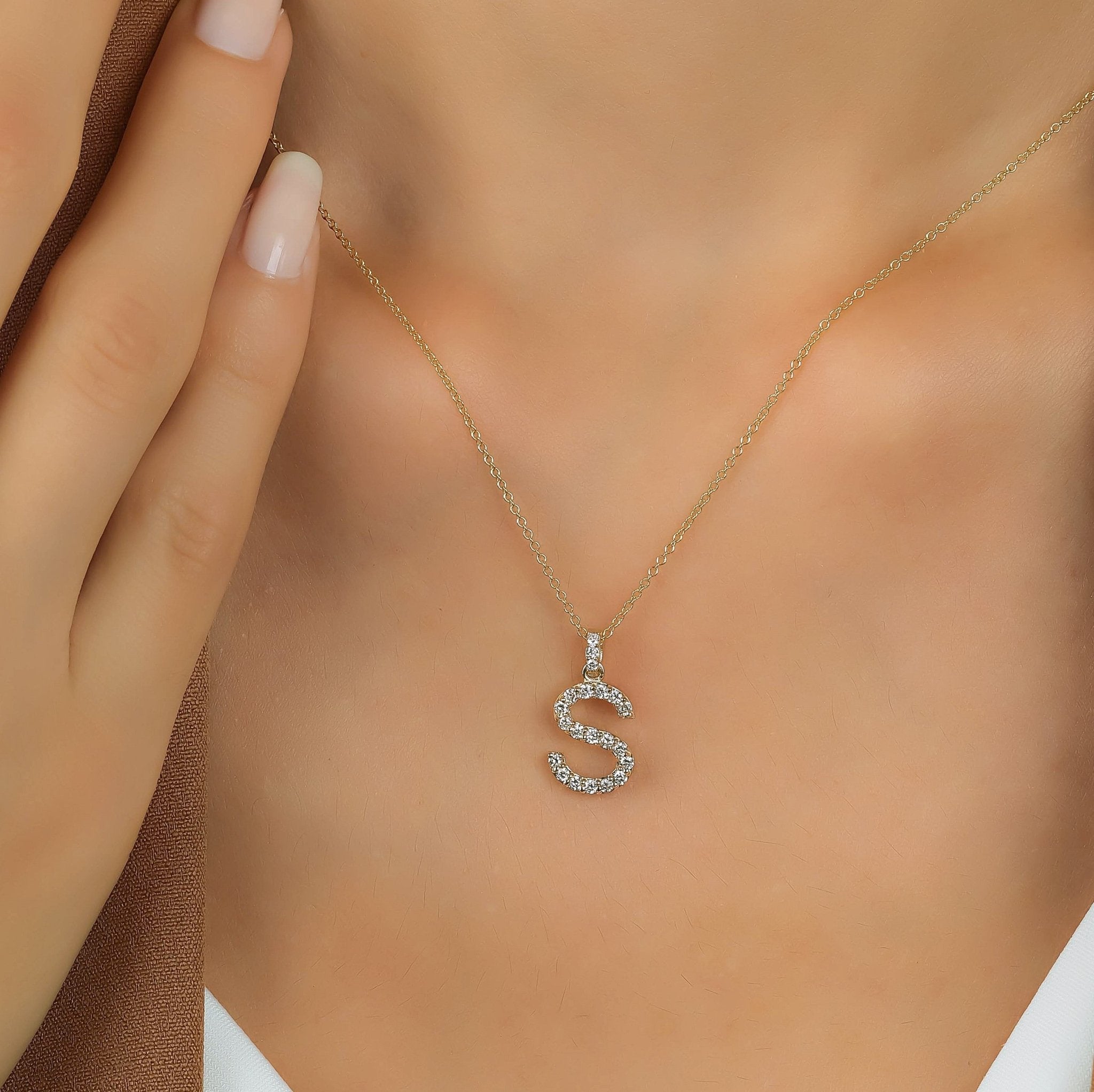 14K yellow gold initial necklace with diamond letter S, 0.30 carats, worn on a model, showcasing sparkling gemstones.