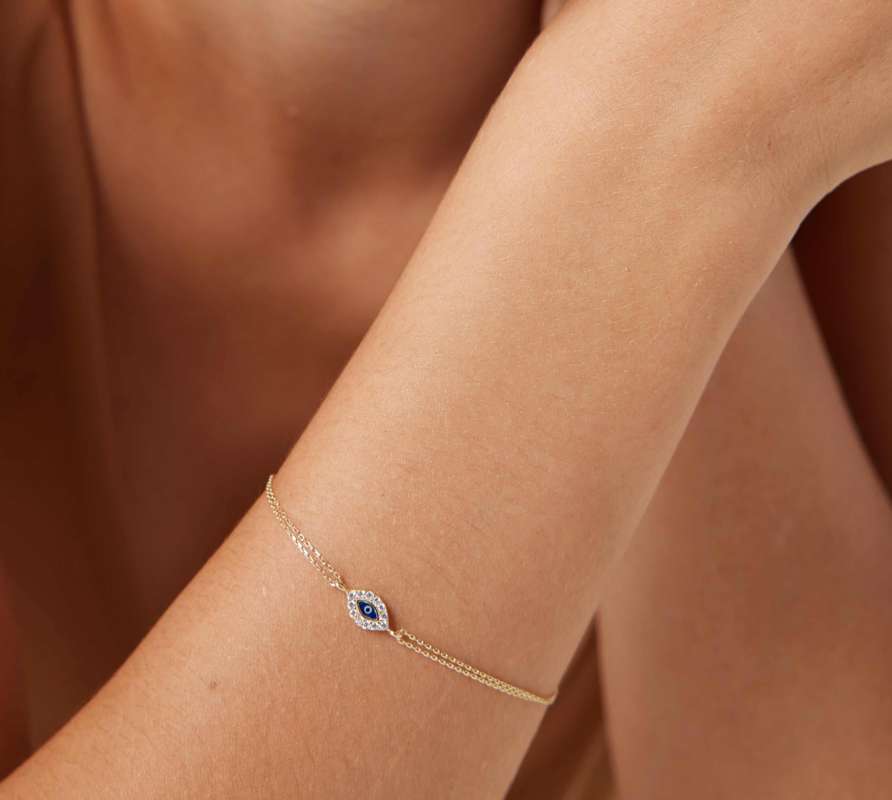 14K yellow gold minimalist evil eye bracelet on a wrist, featuring delicate CZ detail for everyday elegance.