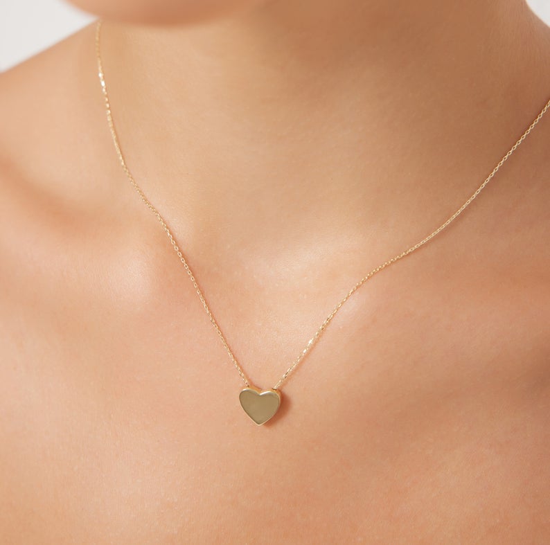Dainty 14K yellow gold minimalist heart necklace worn on a woman's neckline, perfect for everyday elegance.