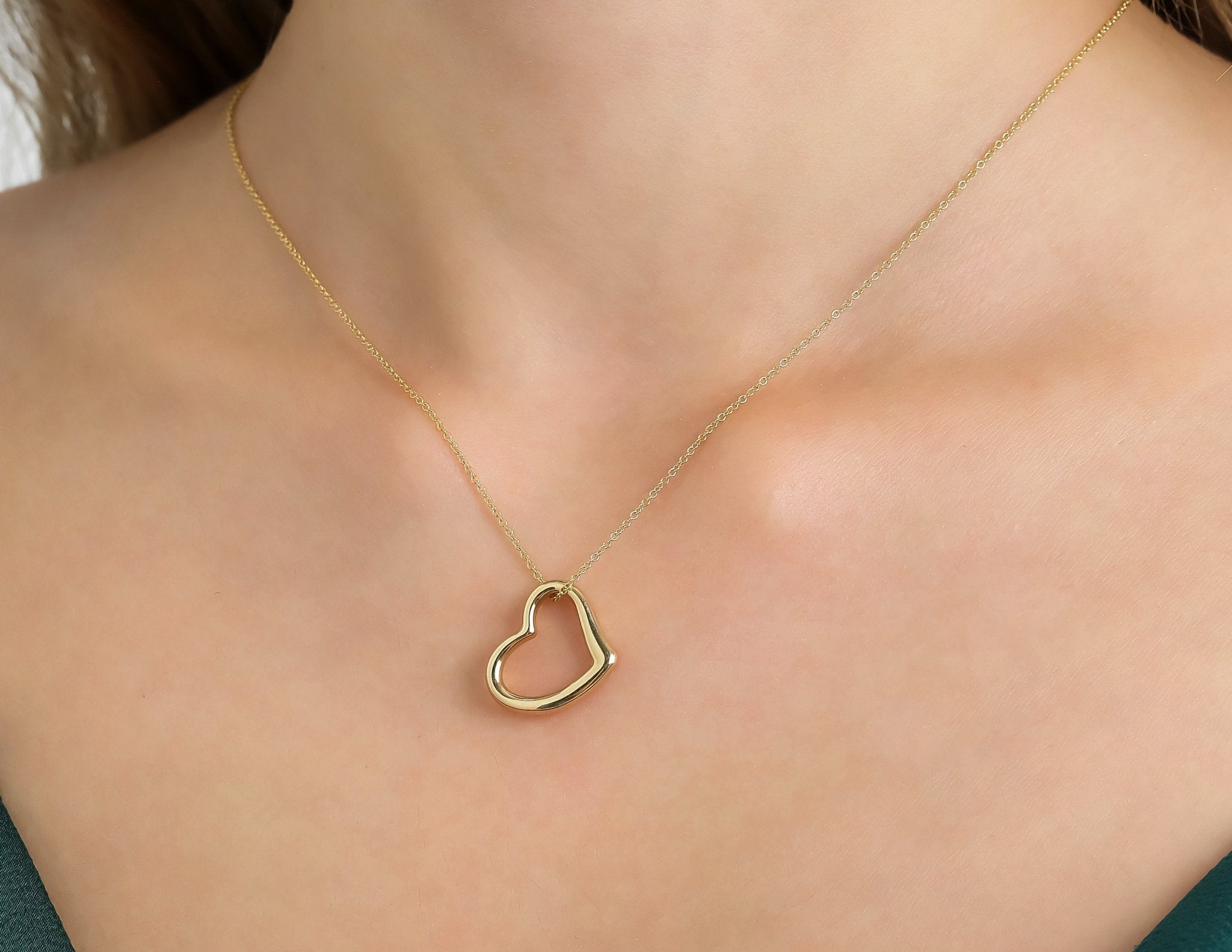 14K yellow gold heart necklace worn on a woman's neck, featuring a delicate open heart design.