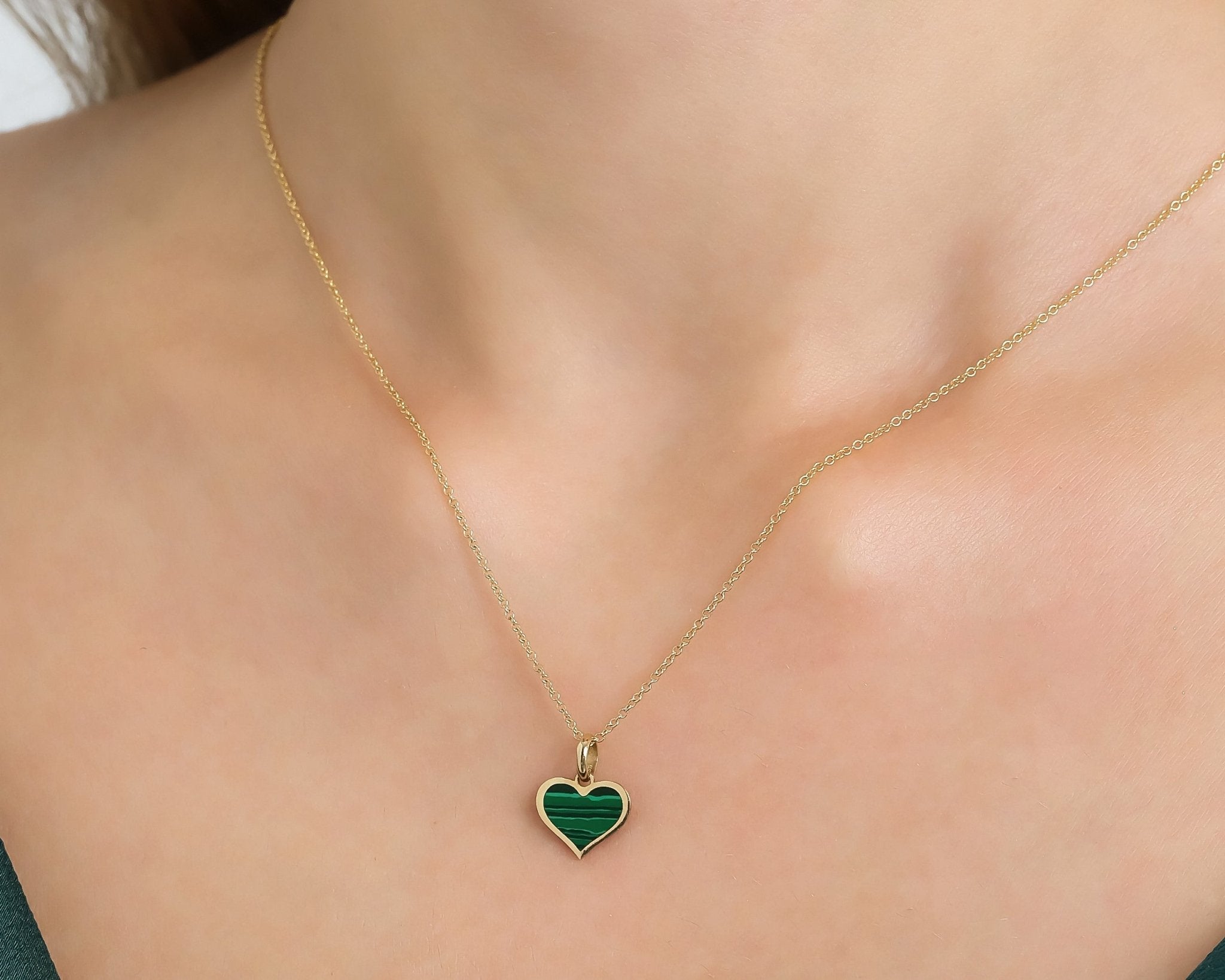 14K yellow gold malachite heart necklace worn on a slender neck, featuring a delicate design and vibrant green color.