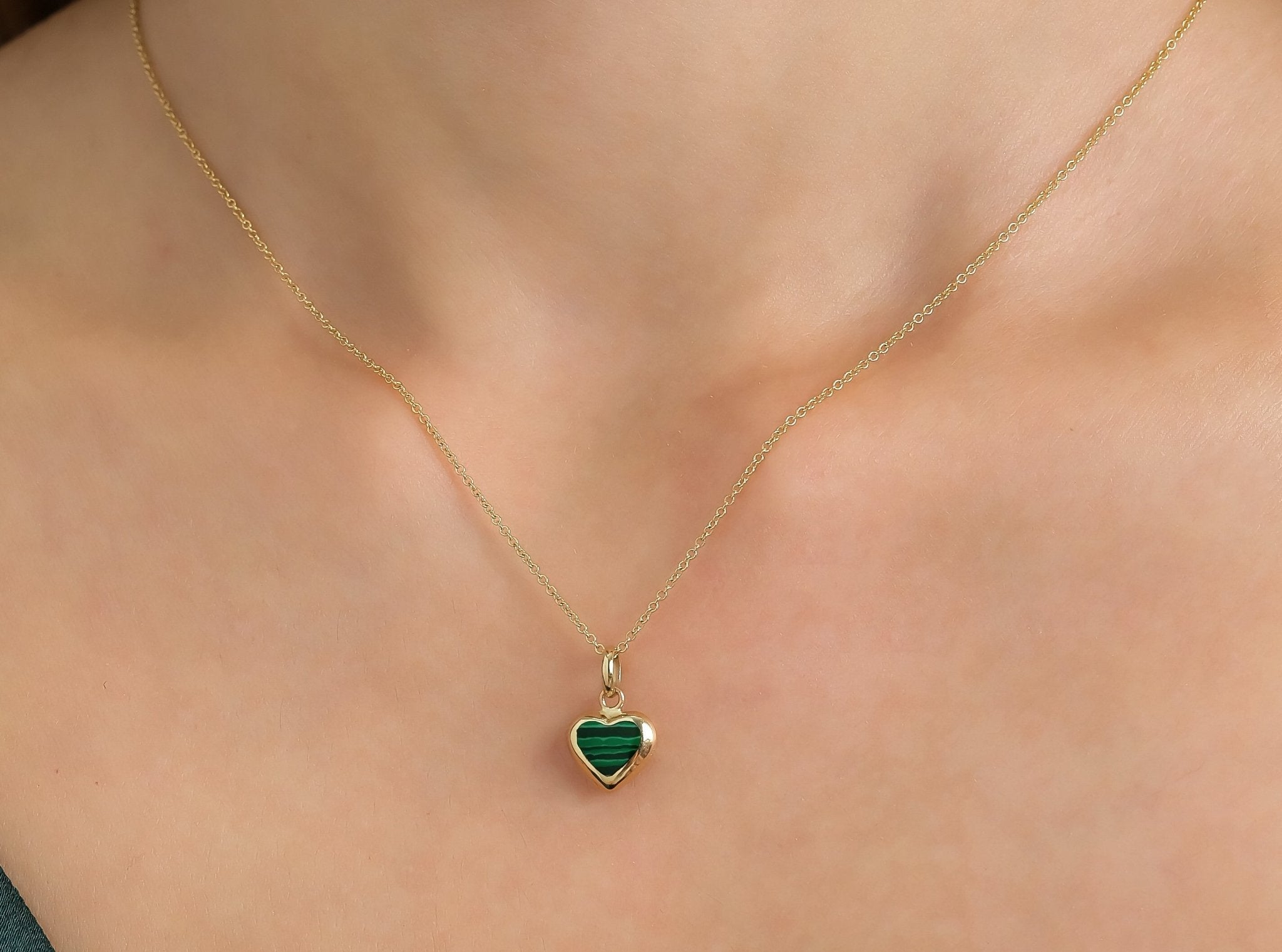 14K yellow gold malachite heart pendant necklace worn on a person's neck, showcasing its dainty and elegant design.