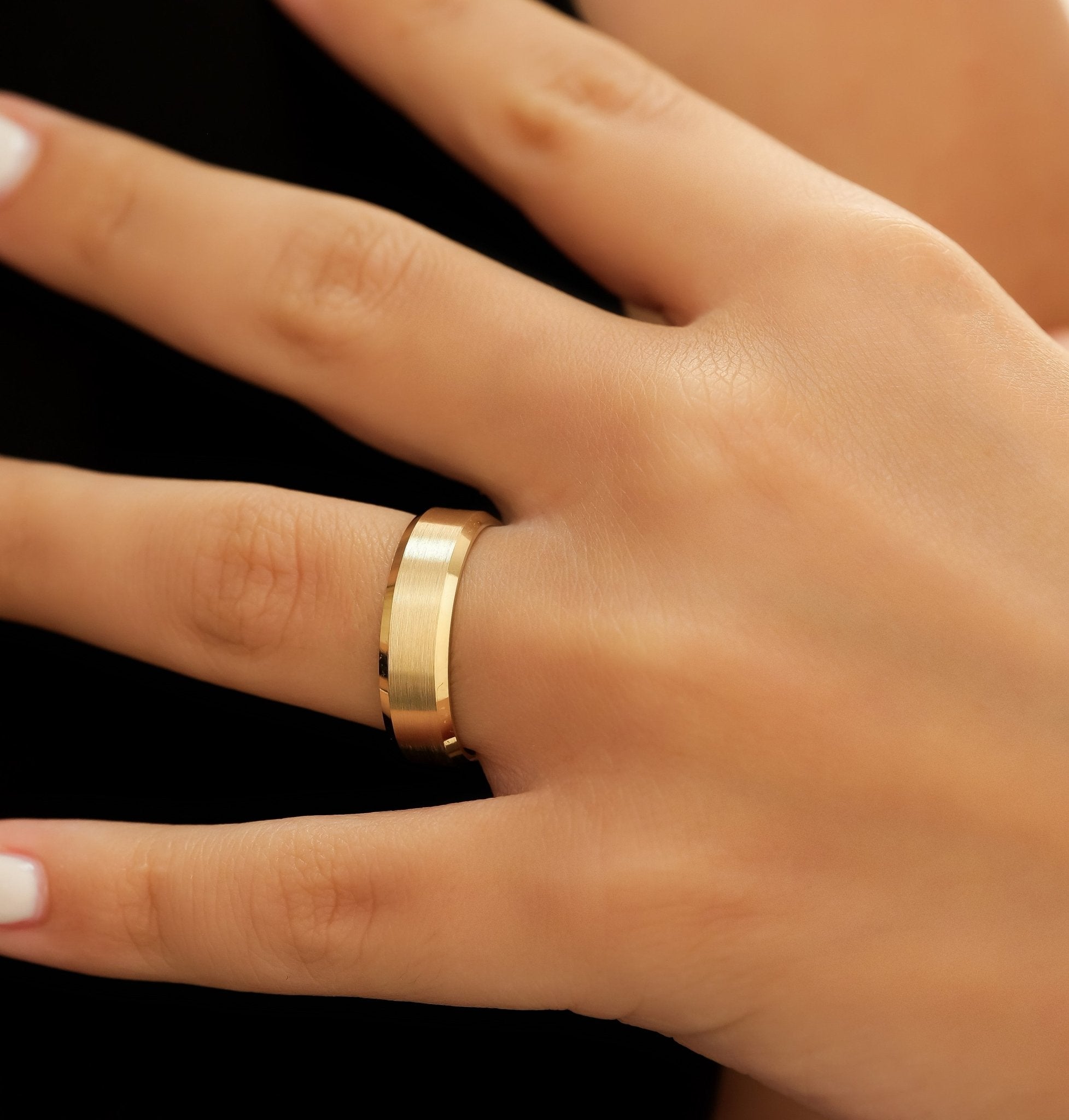 14K yellow gold men's wedding band with a satin finish and shiny beveled edges, shown on a hand.