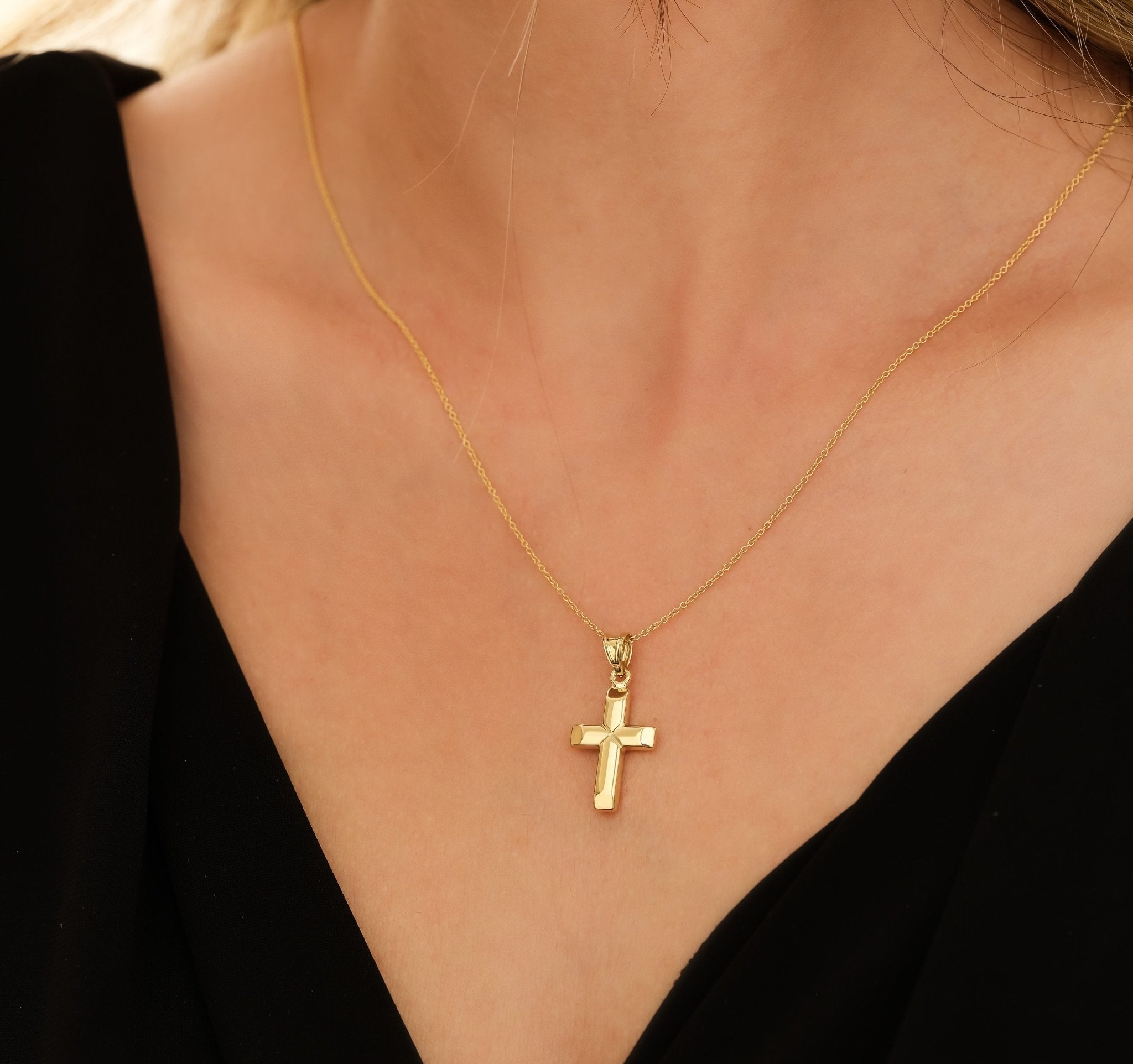 Minimalist 14K yellow gold cross pendant necklace worn on a model, showcasing its delicate and classy design.