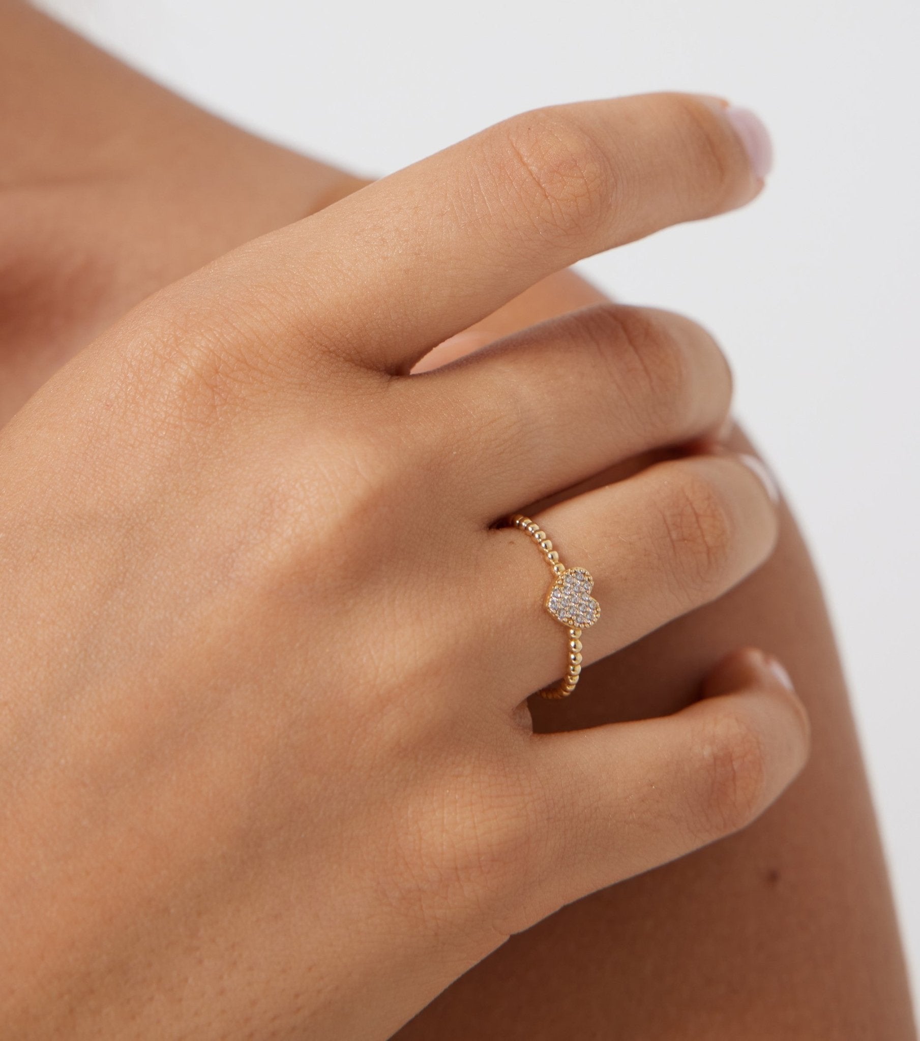 14K yellow gold minimalist diamond heart ring worn on a hand, featuring sparkling white diamonds and delicate band design.