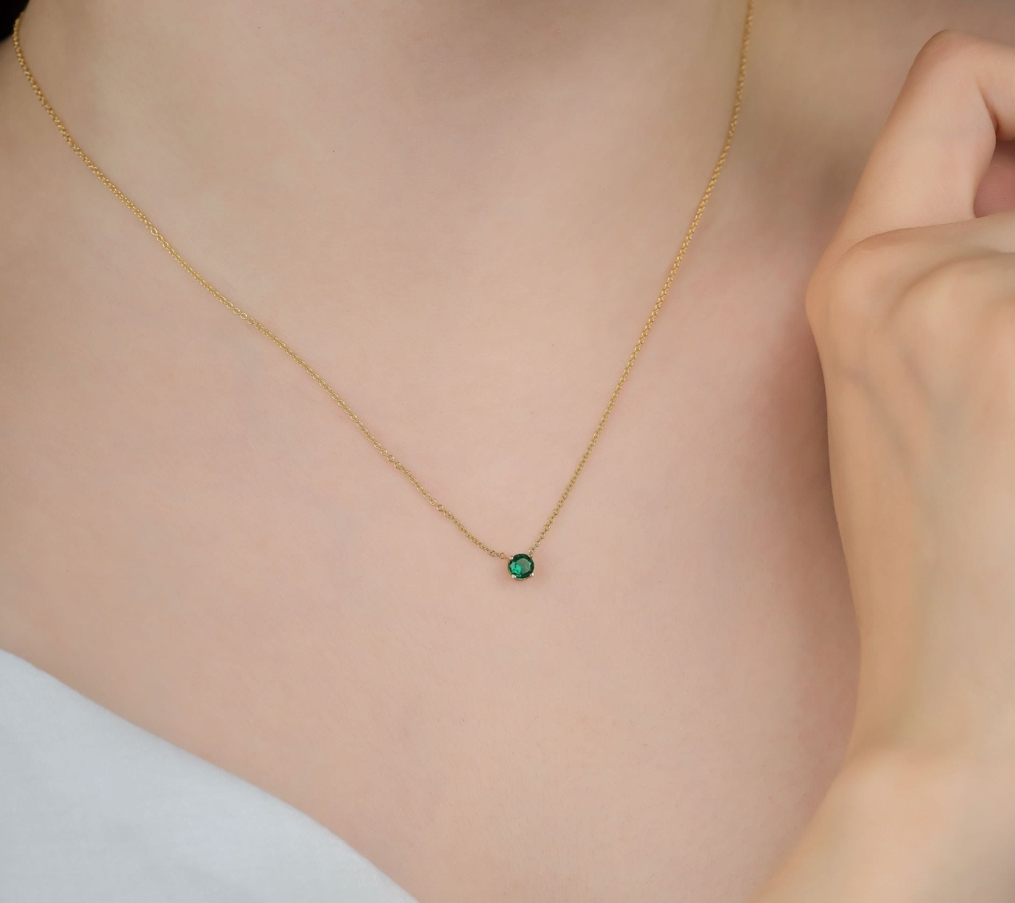 Minimalist 14K yellow gold necklace showcasing a 5mm prong set solitaire emerald pendant, perfect for everyday wear.