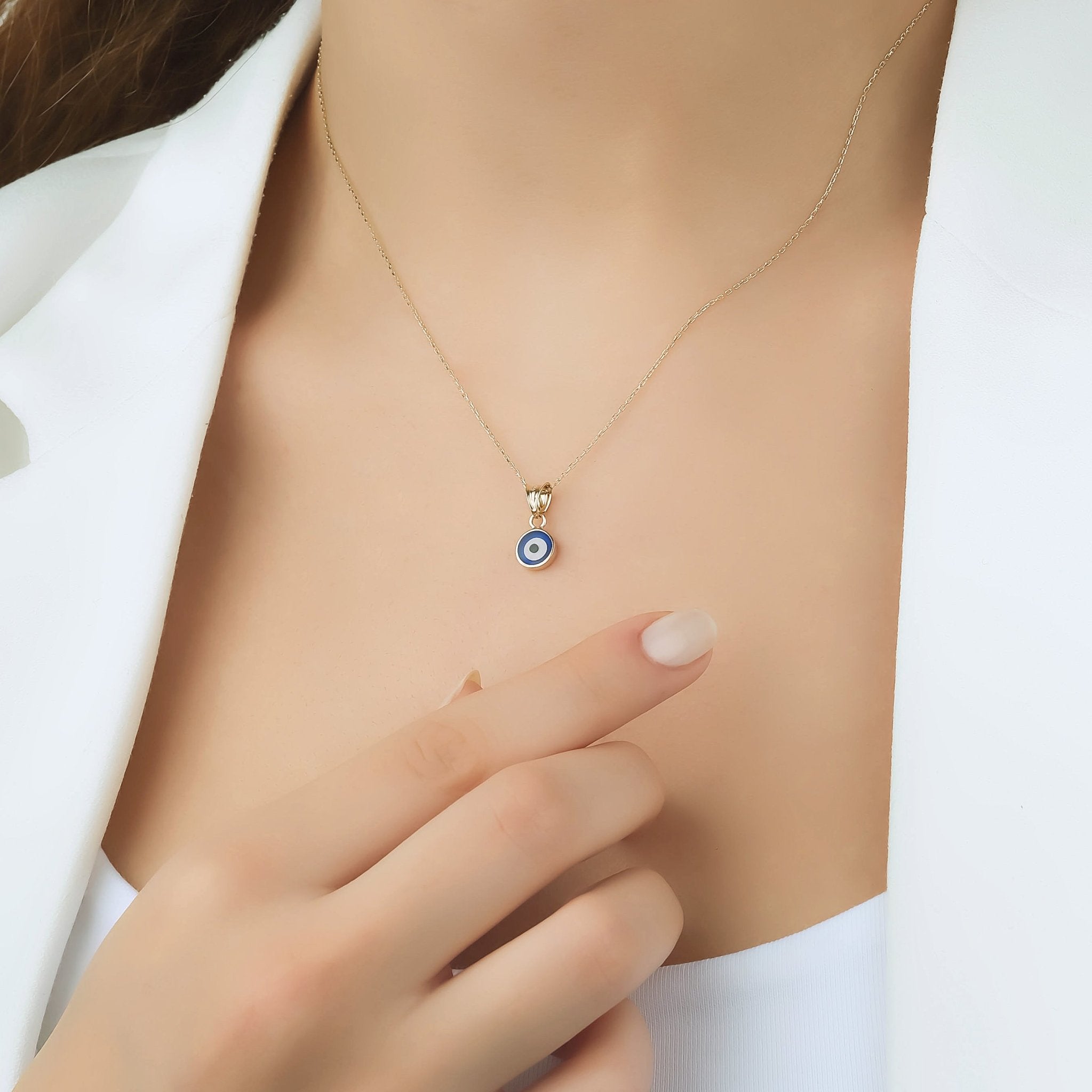 Dainty 14K yellow gold minimalist round evil eye necklace worn by model, showcasing its elegance and simplicity.