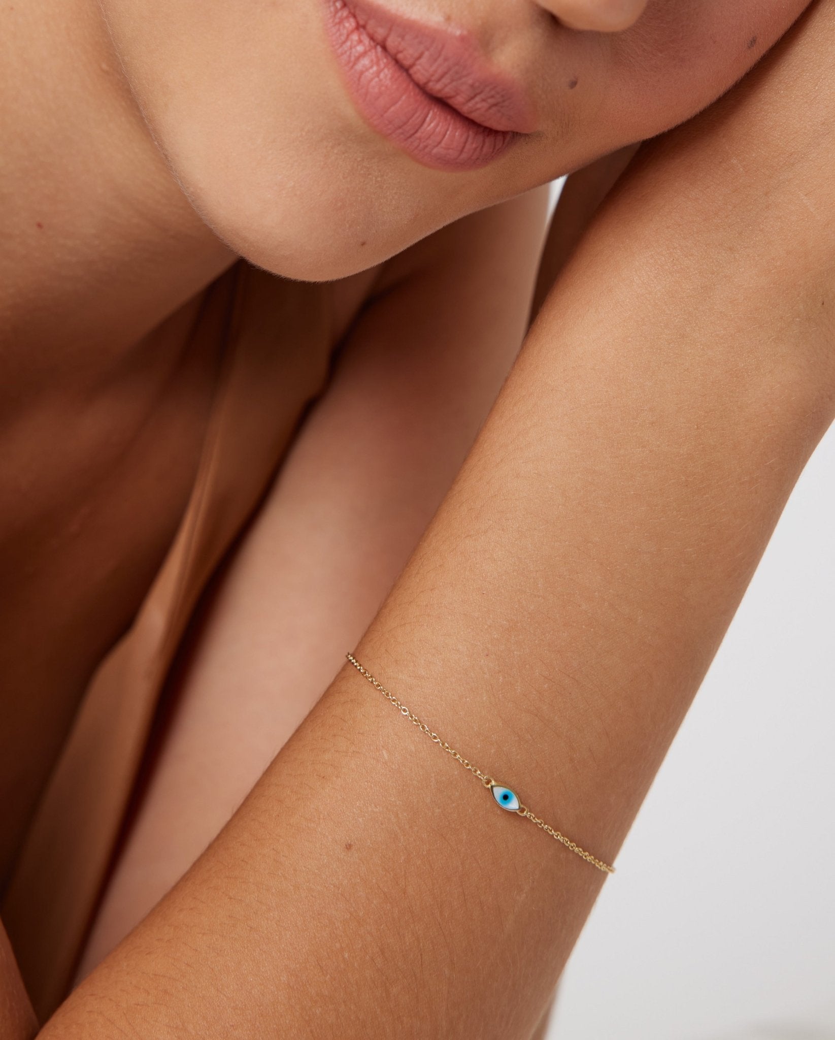 14K yellow gold minimalist evil eye bracelet with white and blue enamel worn on wrist, perfect for everyday use