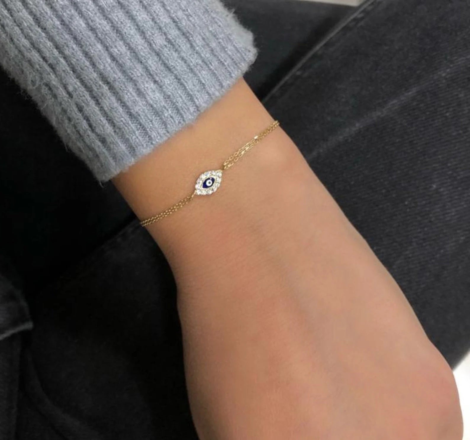 14K yellow gold minimalist evil eye bracelet on wrist, featuring cubic zirconia and delicate design for everyday wear.
