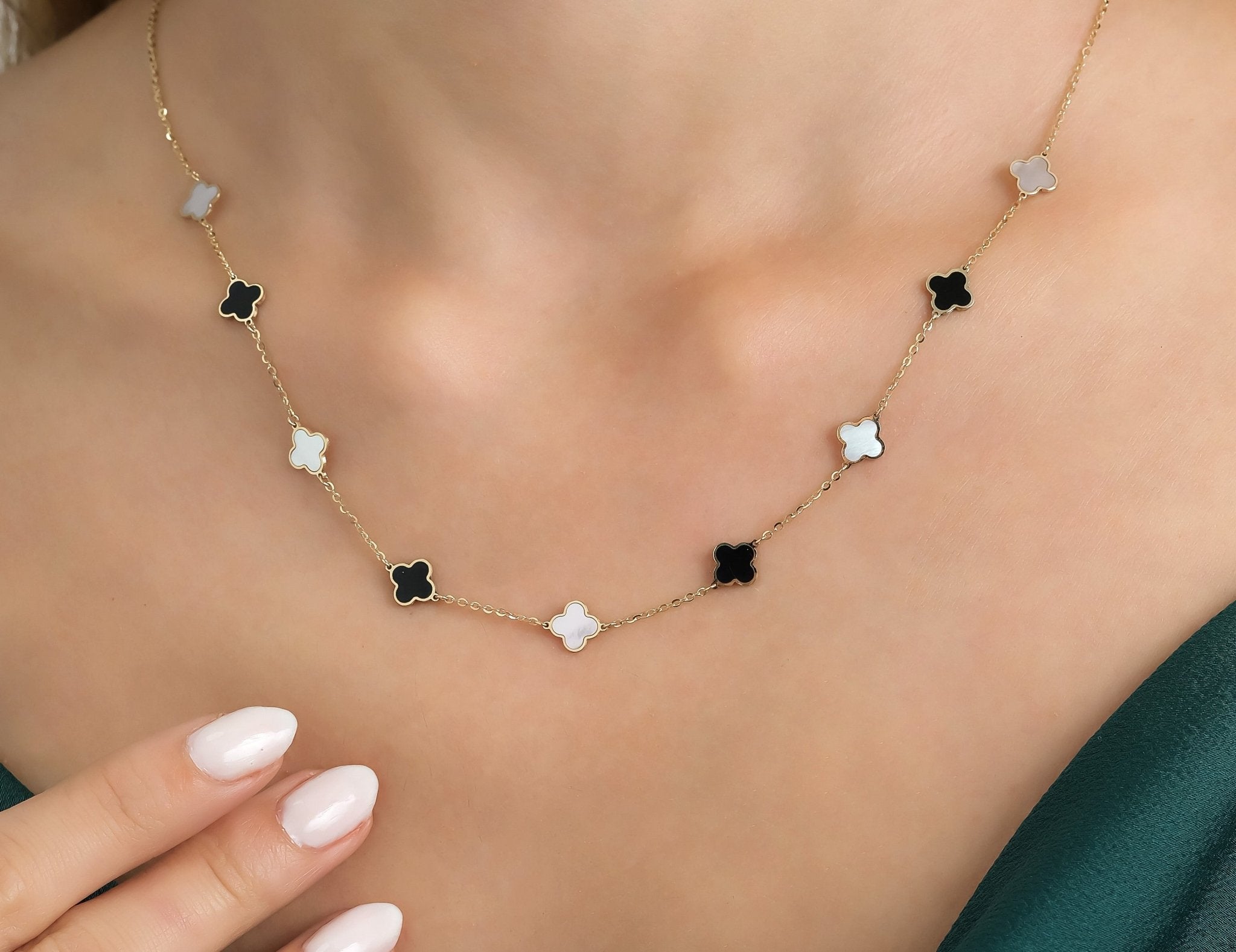 14K yellow gold four leaf clover necklace with mother of pearl and onyx, worn elegantly by a model.