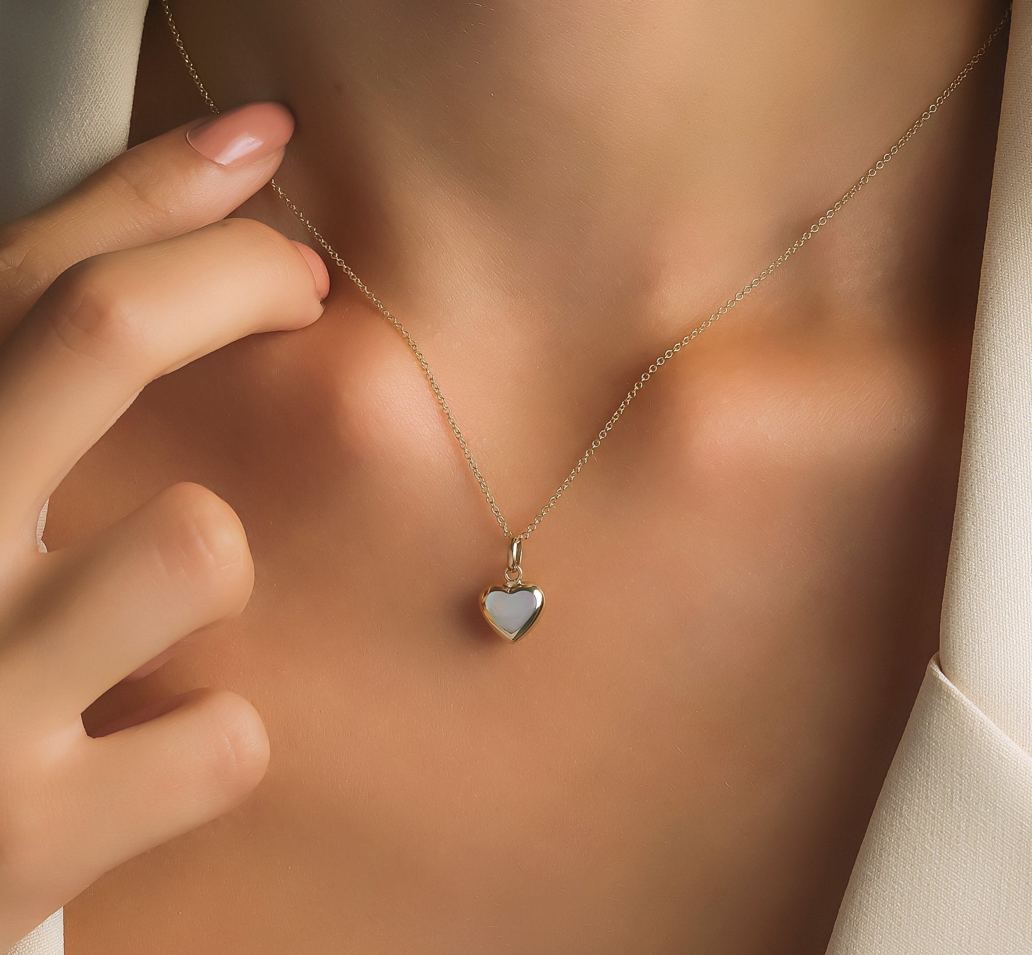 Model wearing 14K yellow gold mother of pearl puffed heart pendant necklace, showcasing its delicate design.