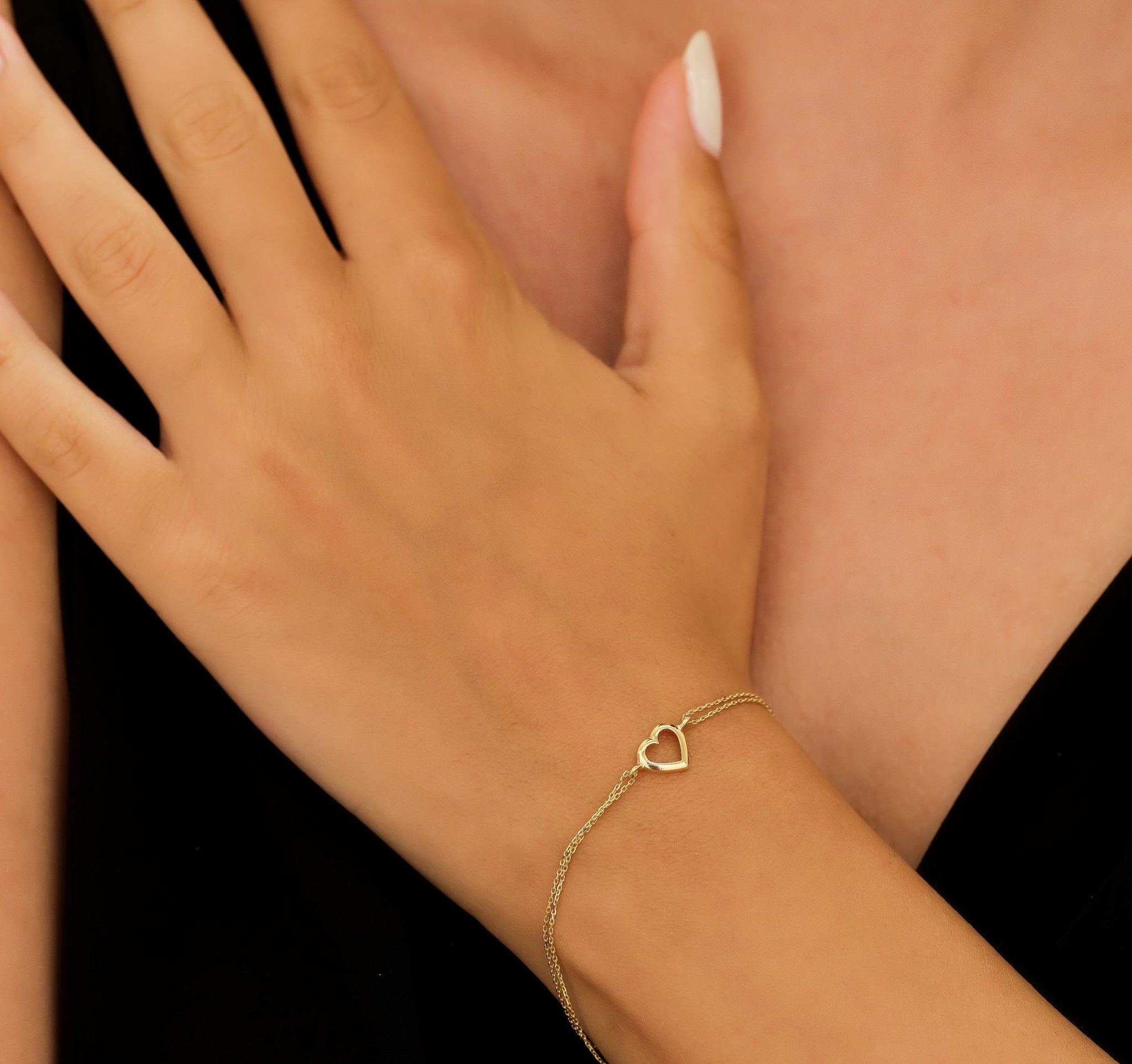Dainty 14K yellow gold open heart bracelet worn on a woman's wrist, showcasing a delicate and classy design.