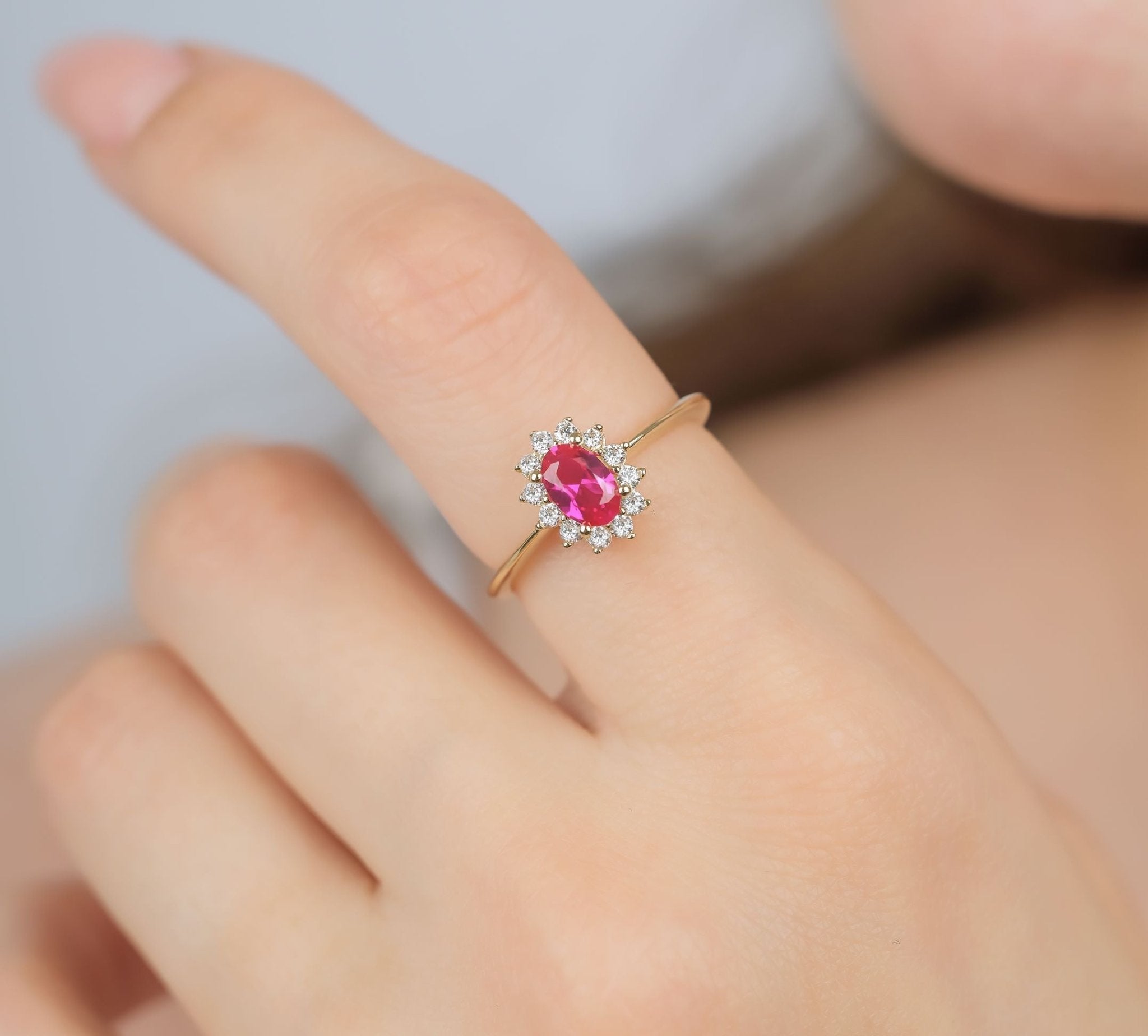 14K yellow gold oval ruby ring with CZ, showcased on a hand, ideal for women's wedding bands, comes in a gift box.