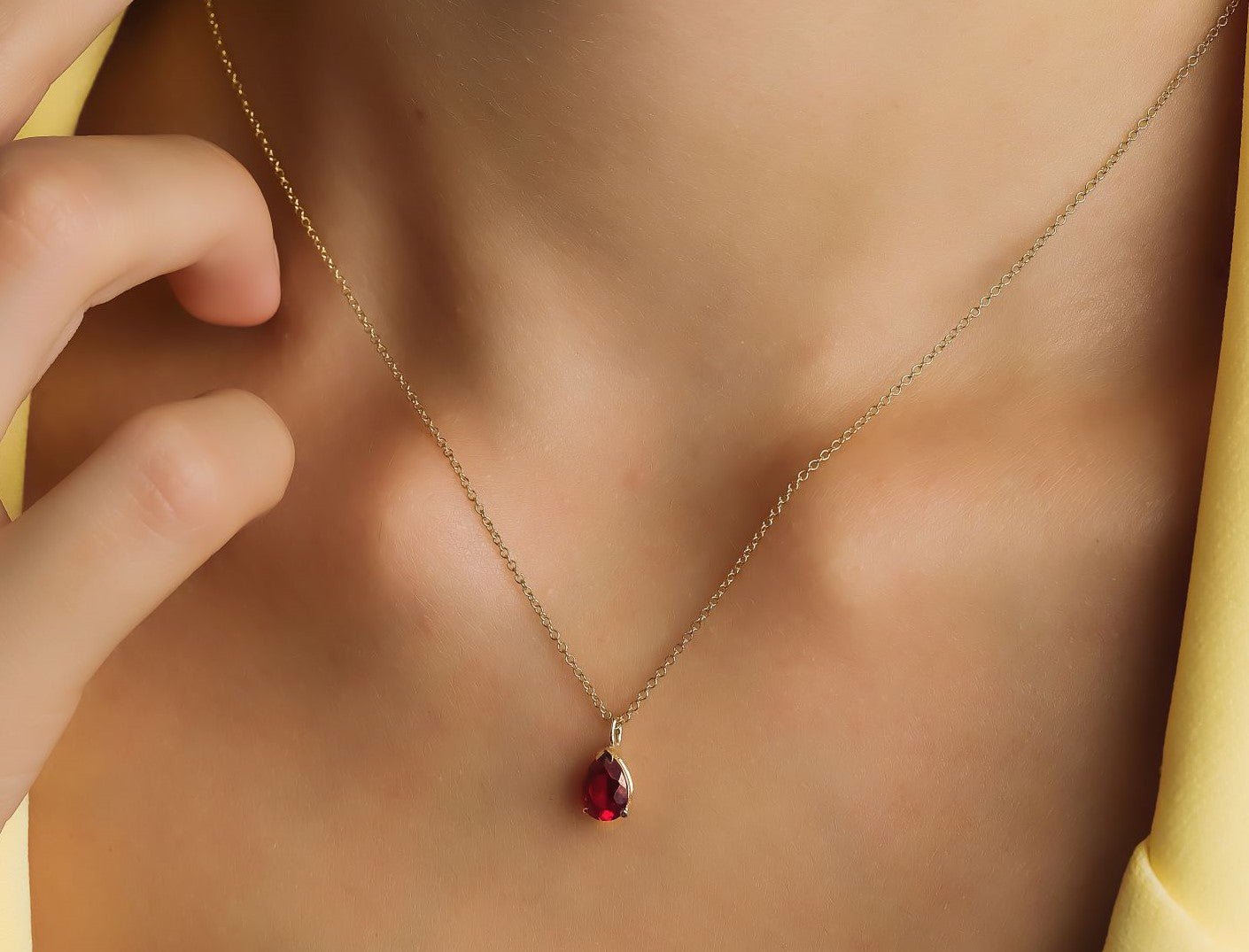 14K yellow gold pear shape solitaire ruby necklace worn, showcasing the elegant prong setting of the lab-created ruby pendant.