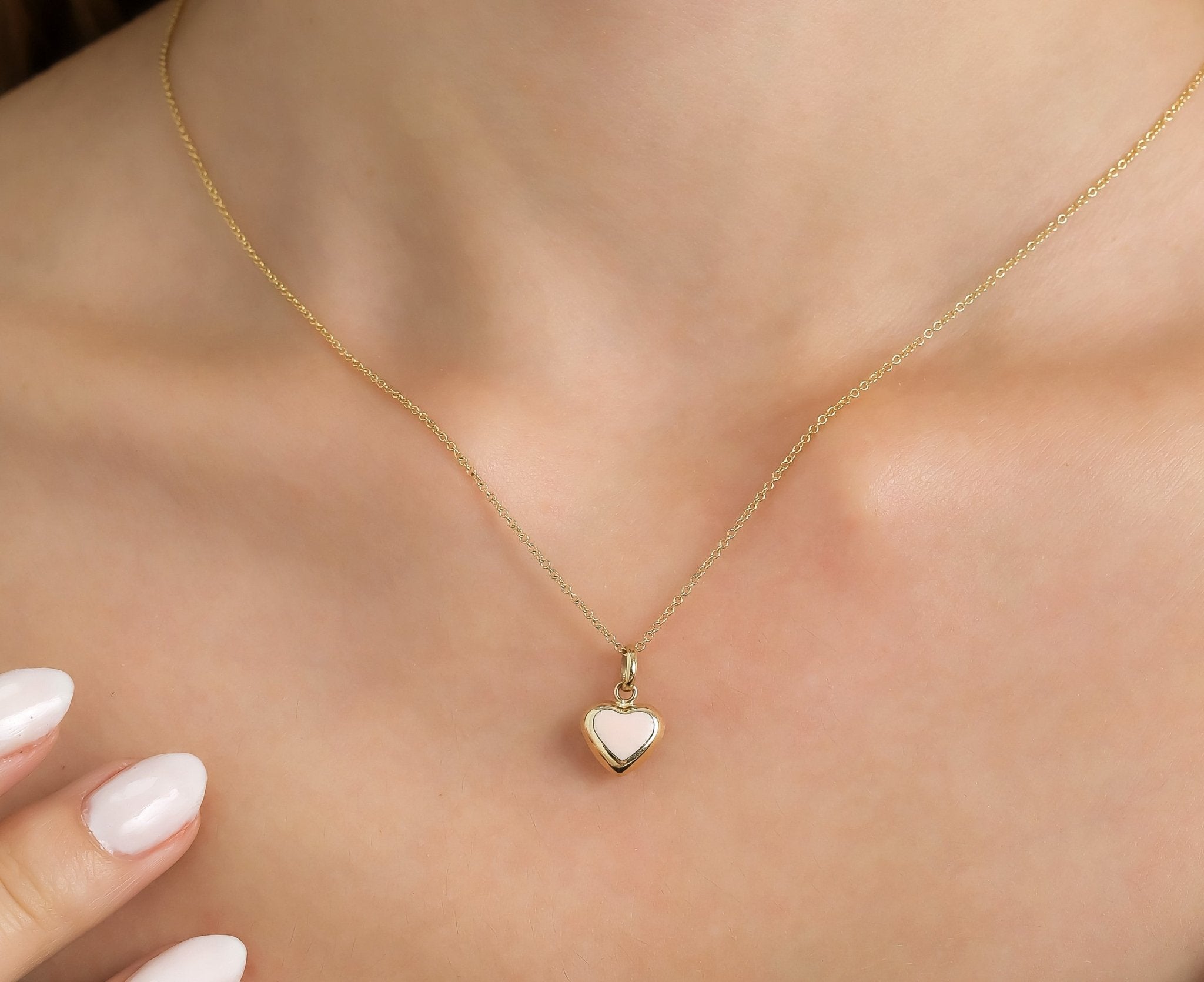 14K yellow gold pink puffed heart pendant necklace worn on a model, showcasing its dainty and elegant design.