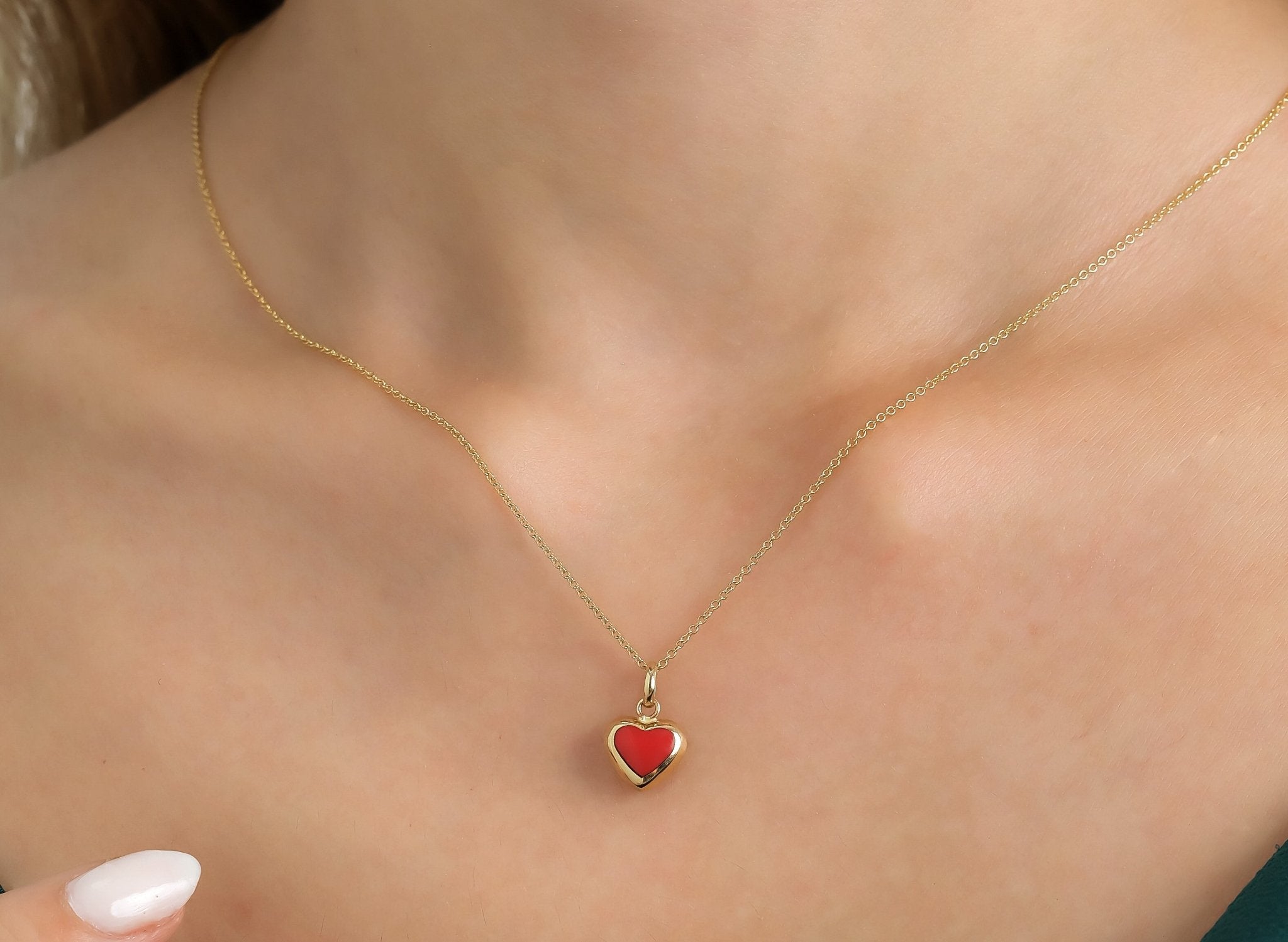 14K yellow gold necklace featuring a red coral puffed heart pendant, elegantly displayed on a woman's neck.