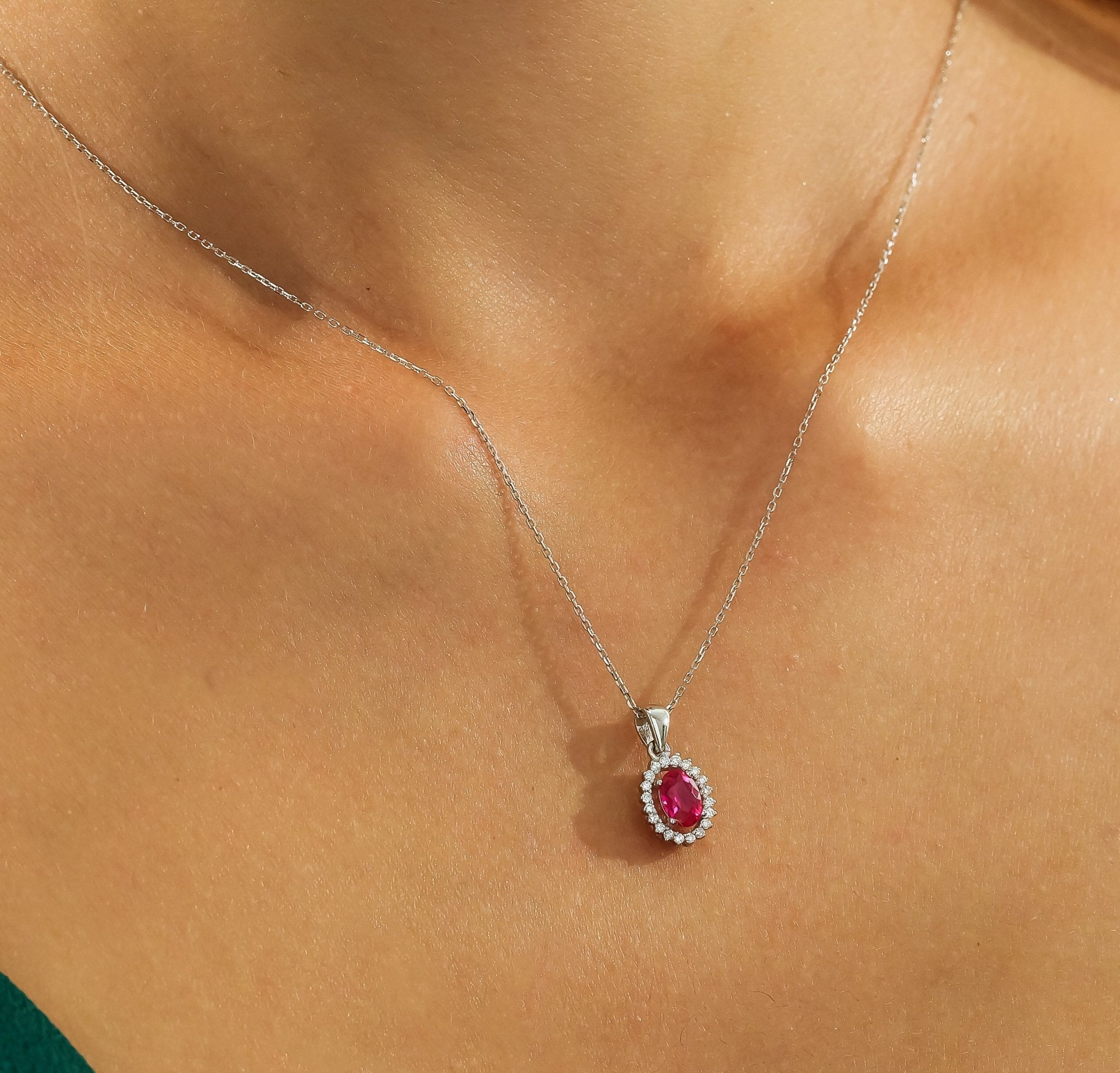 14K yellow gold ruby solitaire necklace with diamond halo, worn elegantly by a model, showcasing its beauty and shine.