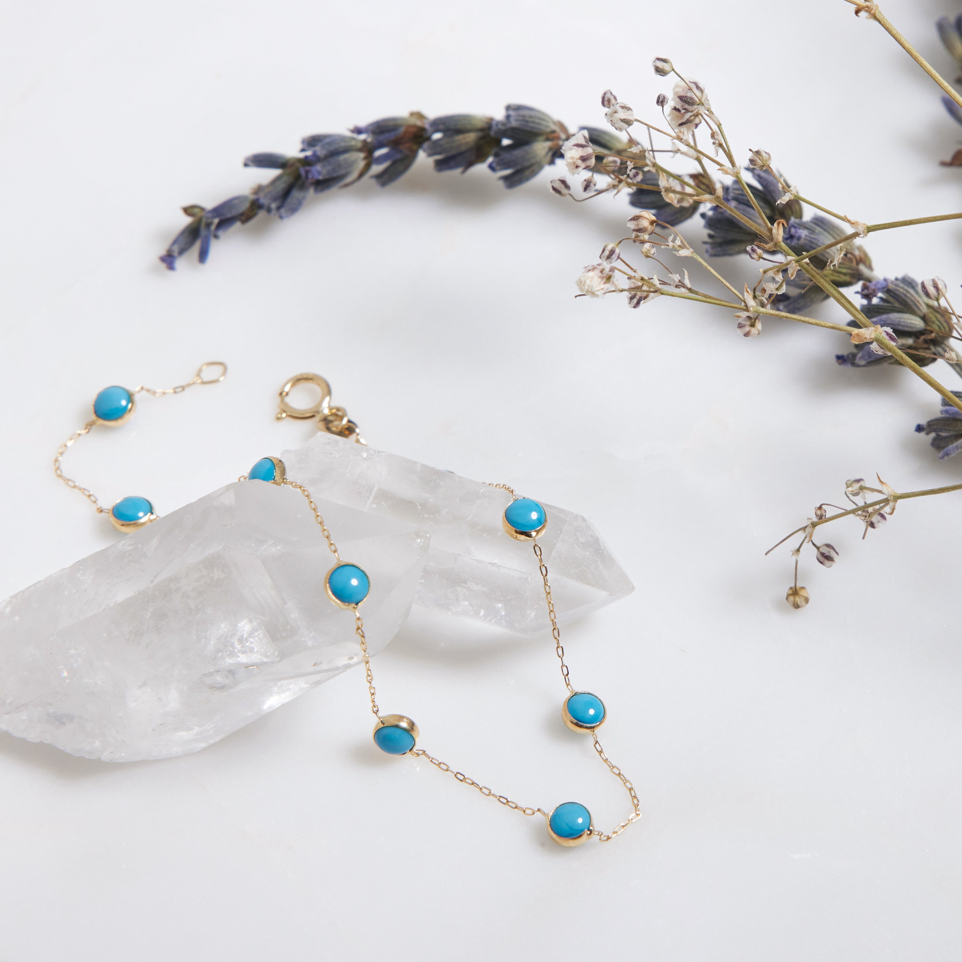 14K Yellow Gold Beaded Station Turquoise Bracelet on a white surface with flowers, showcasing a minimalist design.