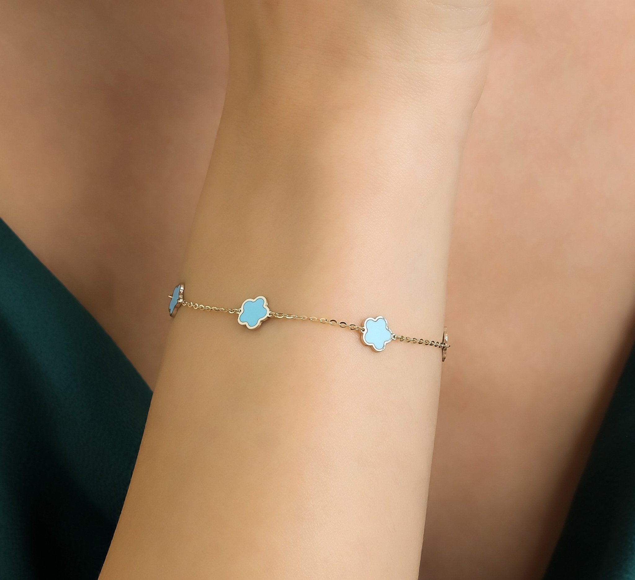 14K yellow gold turquoise blossom bracelet worn on wrist, featuring delicate flower charms against a soft background.
