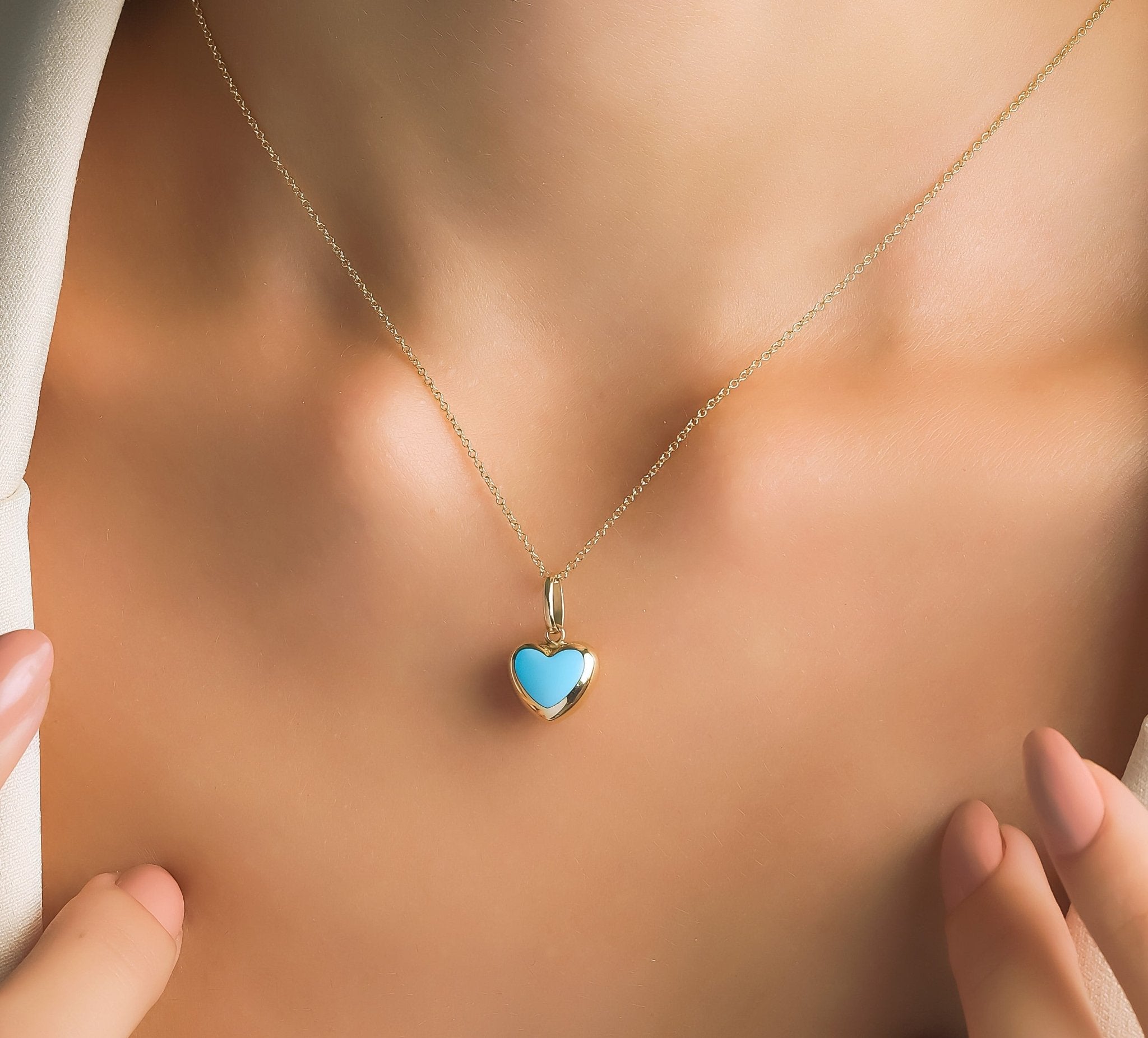 14K yellow gold turquoise puffed heart pendant necklace worn on a model's neckline against a neutral background.