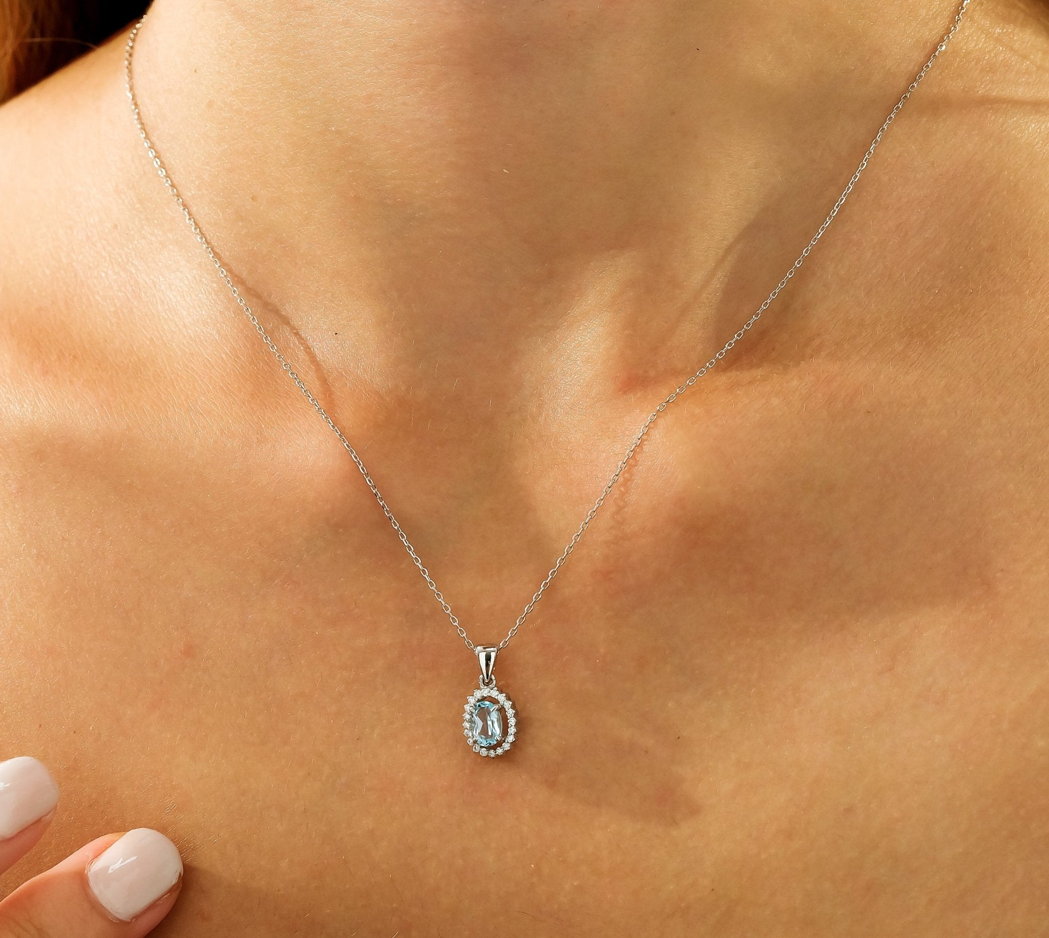 14K yellow gold natural blue topaz solitaire necklace with diamond accents, elegantly worn on model.