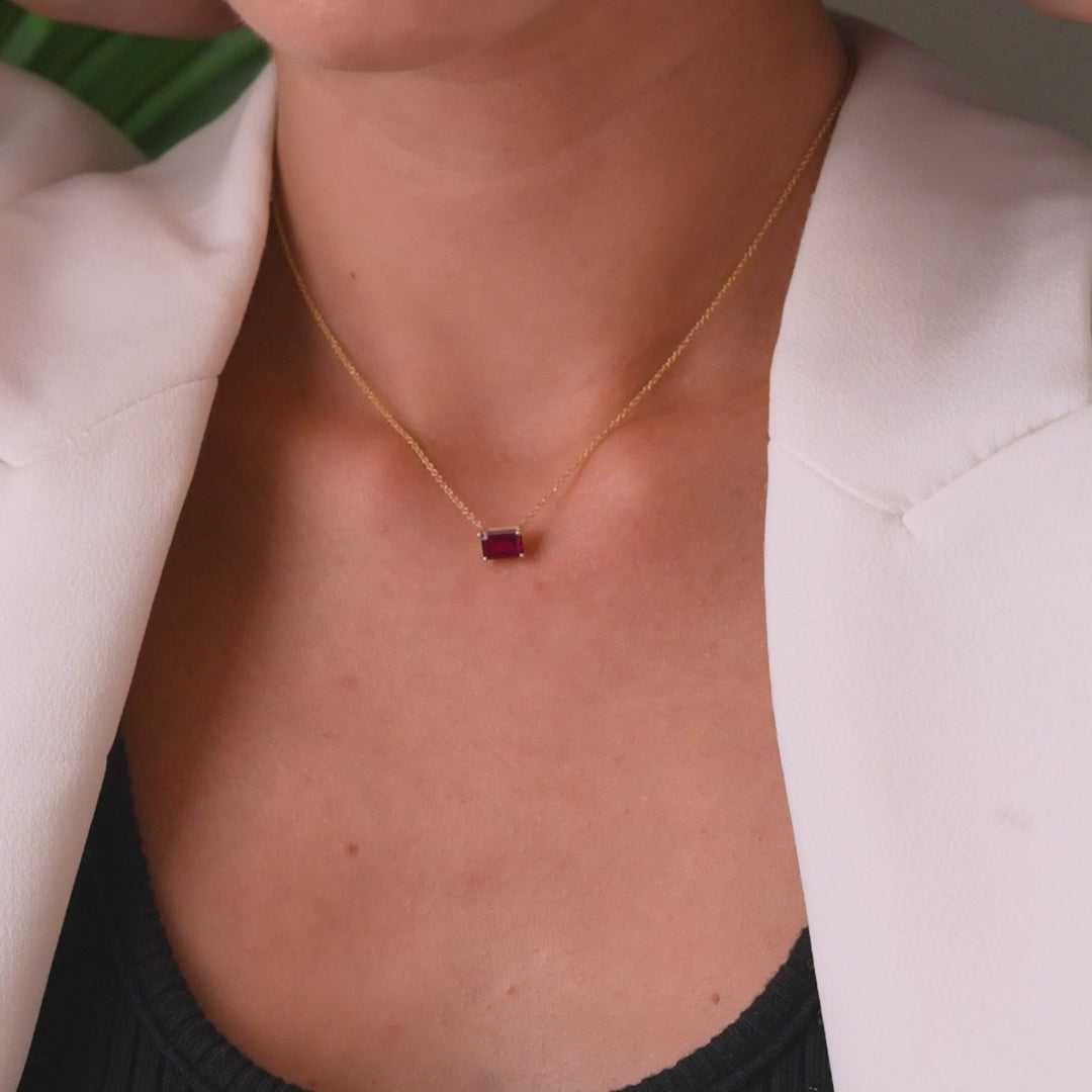 14K solid yellow gold minimalist necklace featuring a prong-set ruby solitaire pendant on a model.