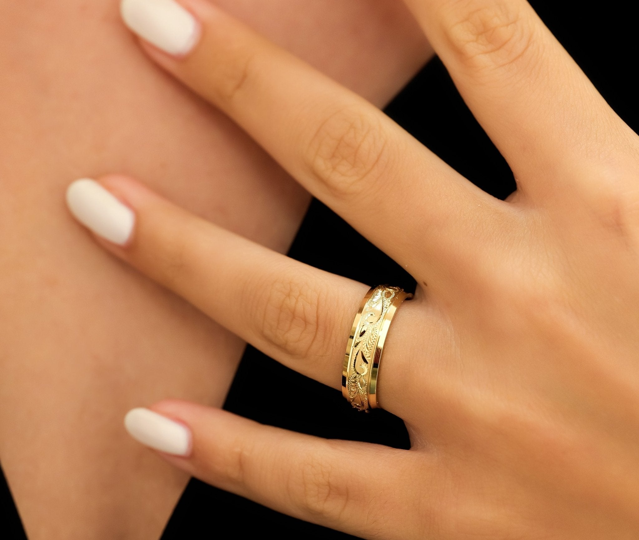 Gorgeous 6mm hand engraved solid yellow gold wedding band with leaf motifs on a model's hand.