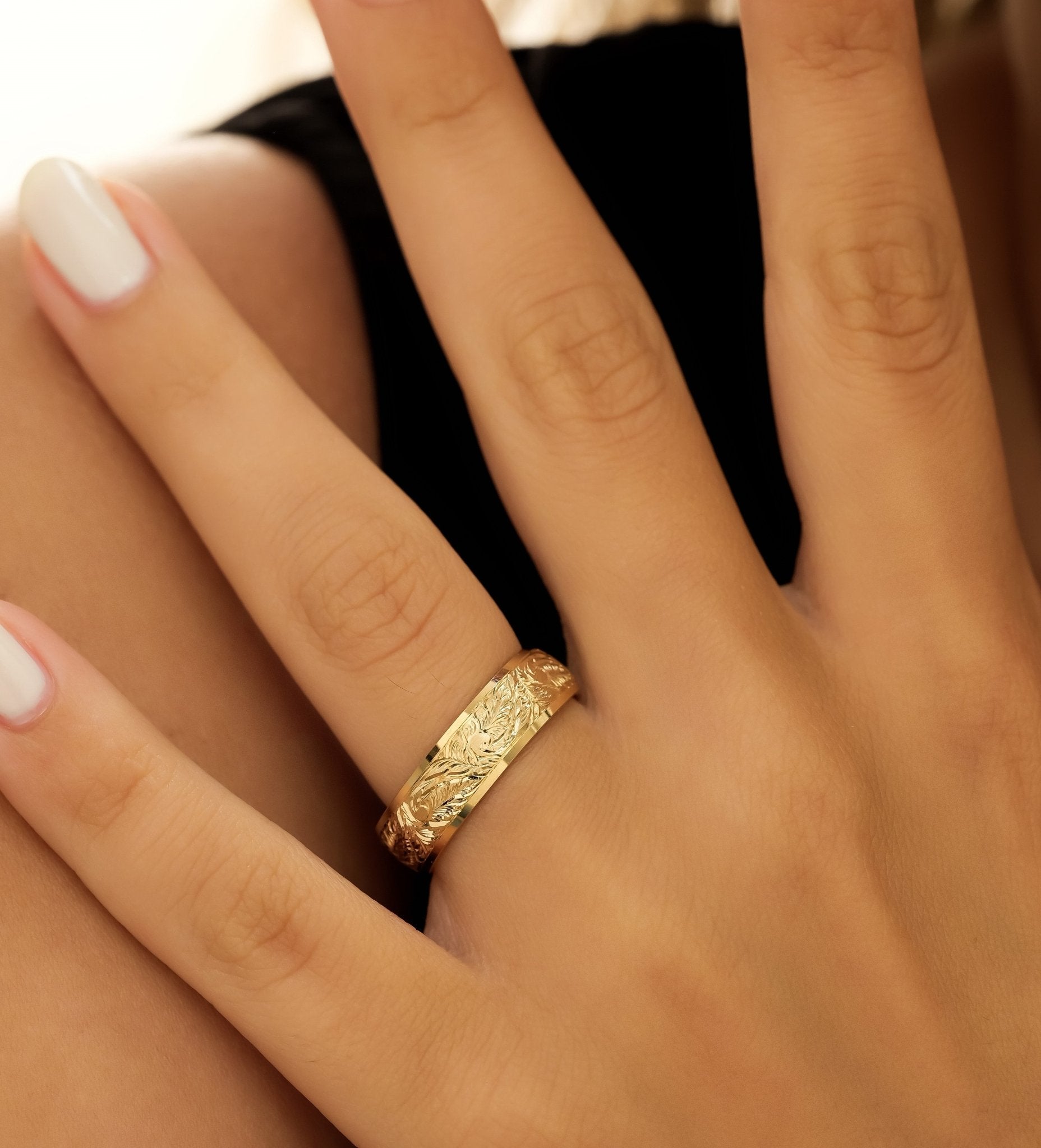 Hand wearing a 6mm yellow gold engraved wedding ring with leaf motifs, showcasing comfort fit and elegant design.