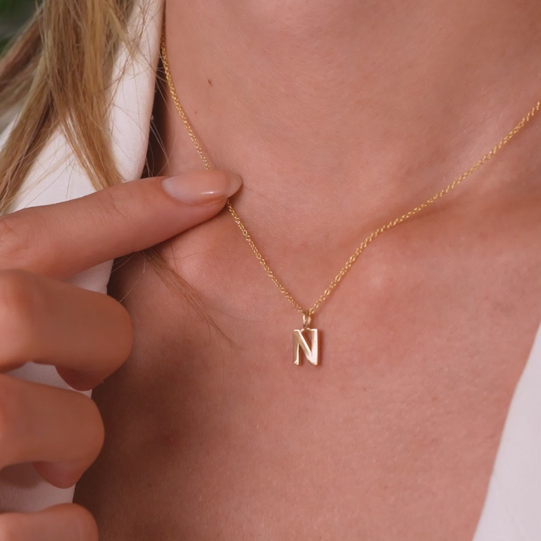 14K solid yellow gold initial necklace featuring letter N, dainty design, shown worn on a model.