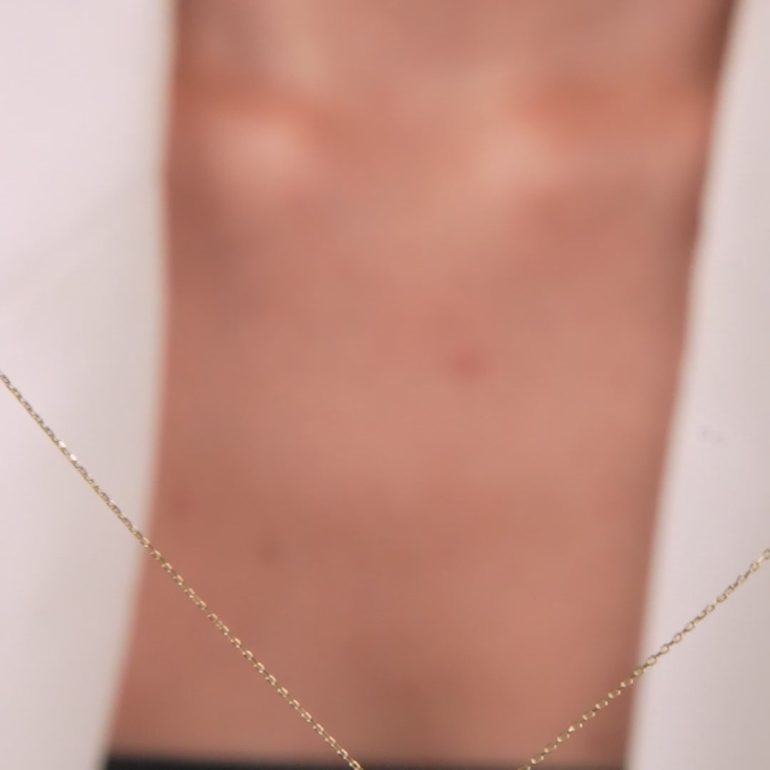 14K solid yellow gold emerald necklace displayed on a model's neck, highlighting its dainty and minimalist design.
