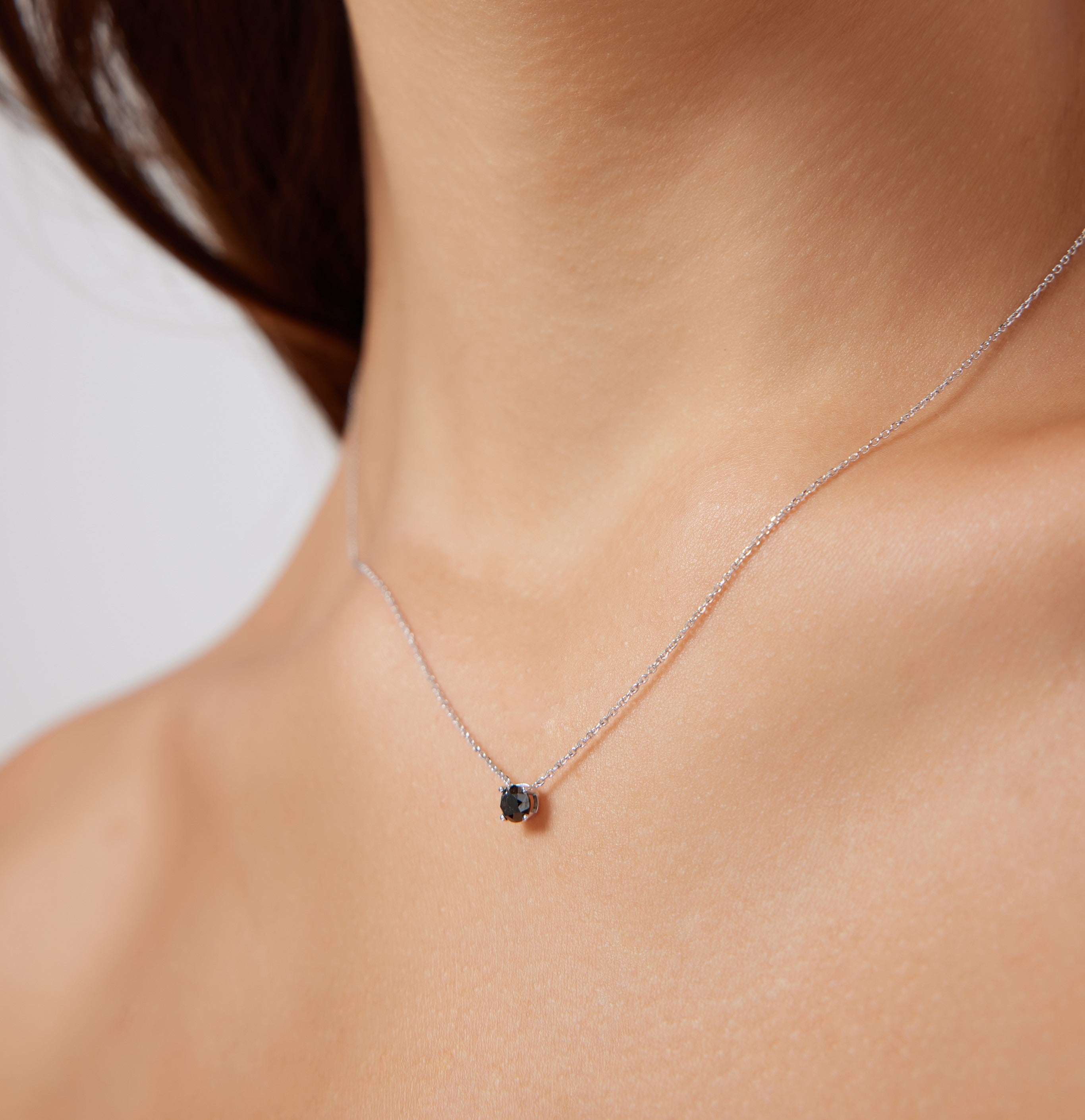 14K white gold minimalist black diamond solitaire necklace displayed on a model's neck, showcasing elegant simplicity.
