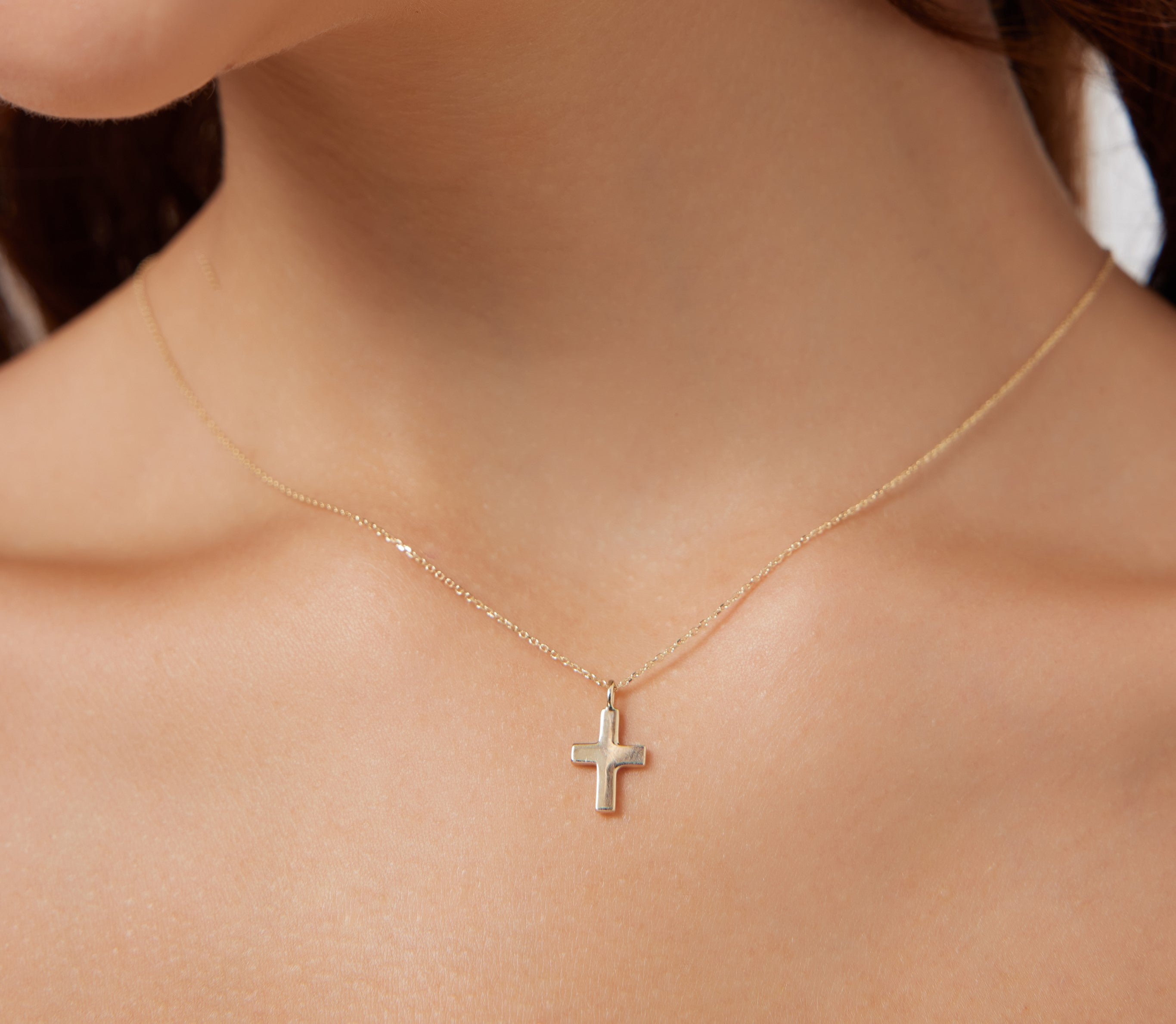 14K solid yellow gold dainty cross necklace worn on model, showcasing minimalist design and 16-inch chain.
