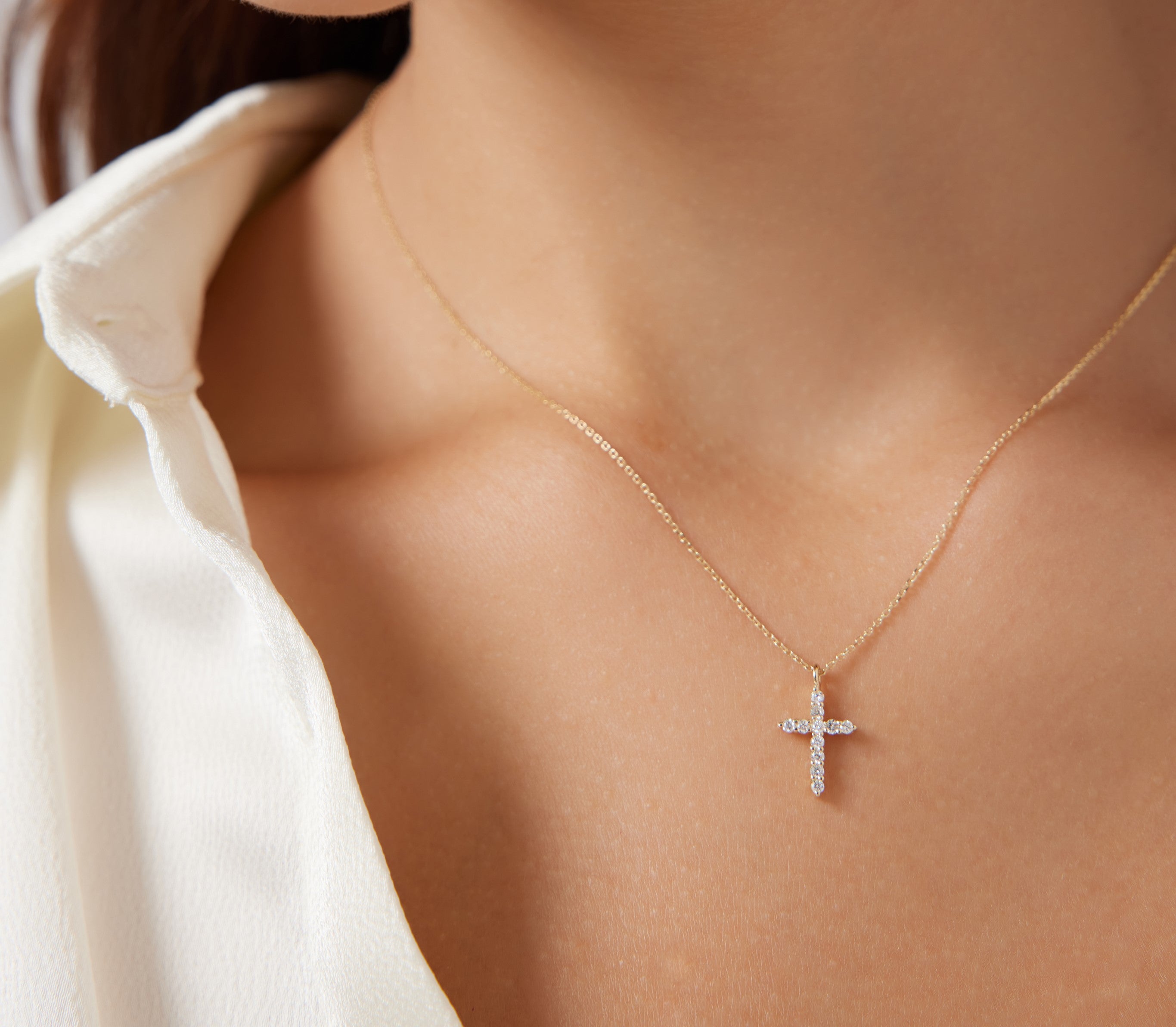 14K solid yellow gold minimalist cross necklace with diamonds worn on a woman, showcasing elegance and simplicity.