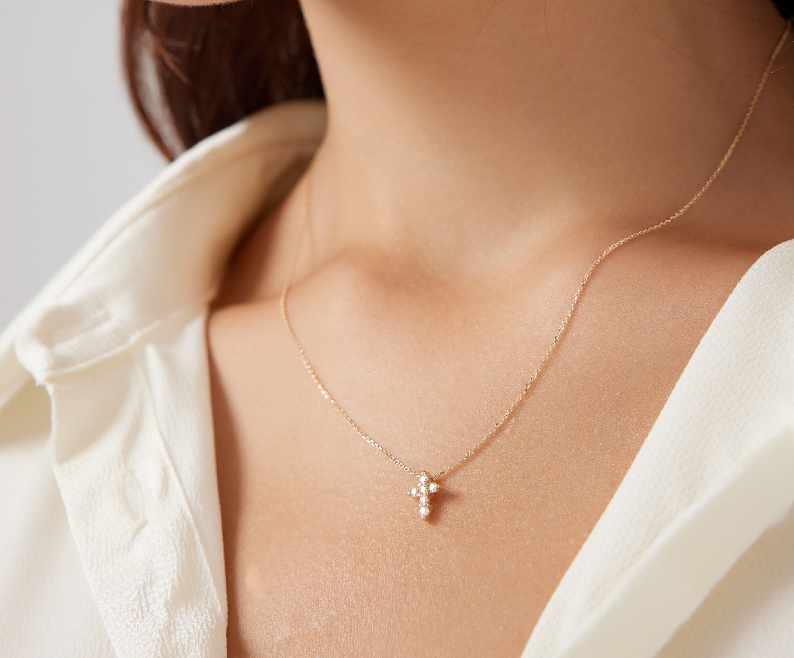 Dainty diamond cross necklace worn by a woman, showcasing its elegant design and minimalist style.