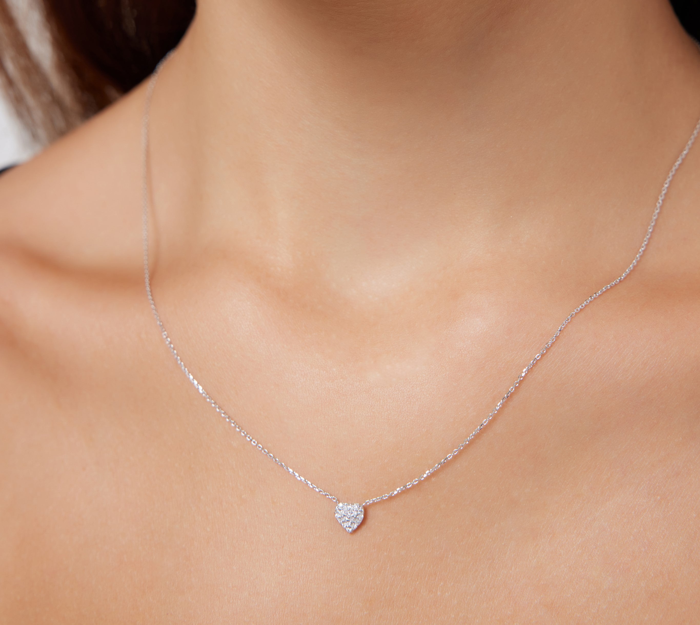 Elegant 14K solid white gold minimalist diamond heart necklace worn on neck, featuring sparkly diamonds in heart pendant.