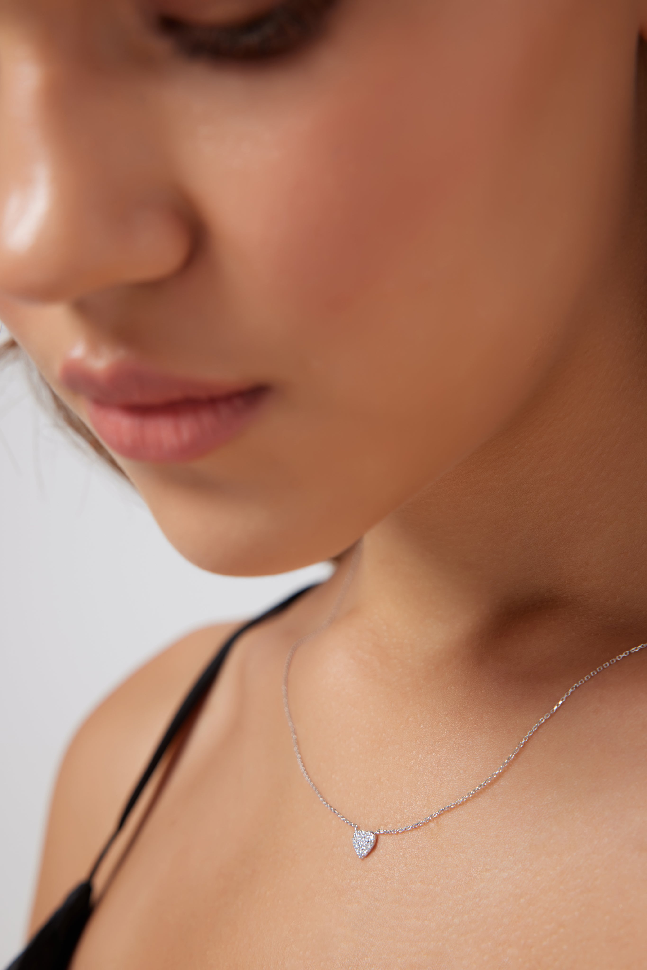 Minimalist 14K solid white gold diamond heart necklace worn by a model, showcasing its delicate design and sparkle.