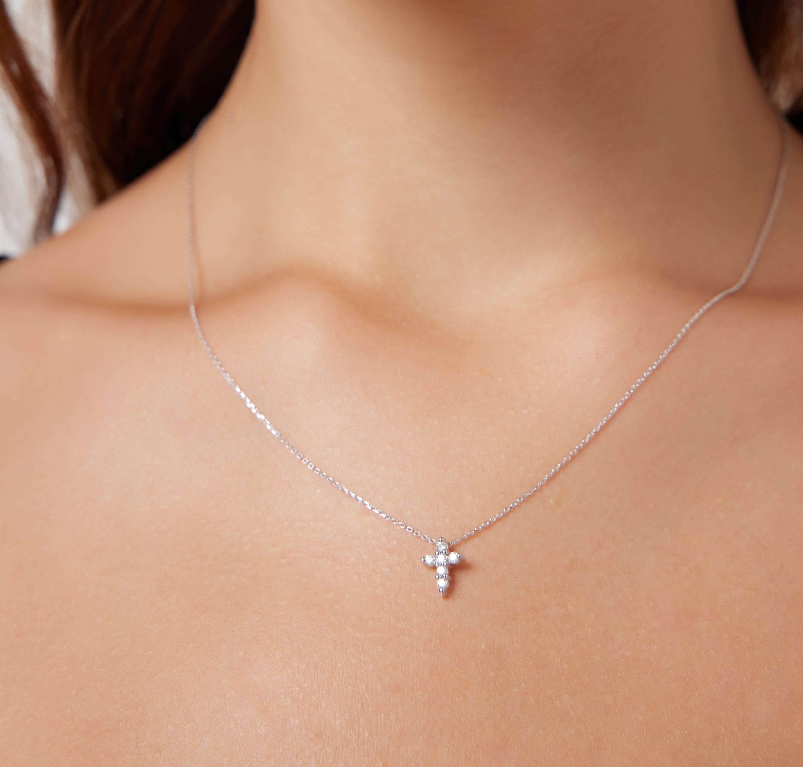 14K solid white gold minimalist diamond cross necklace worn on a woman's neck, showcasing elegant design and sparkle.