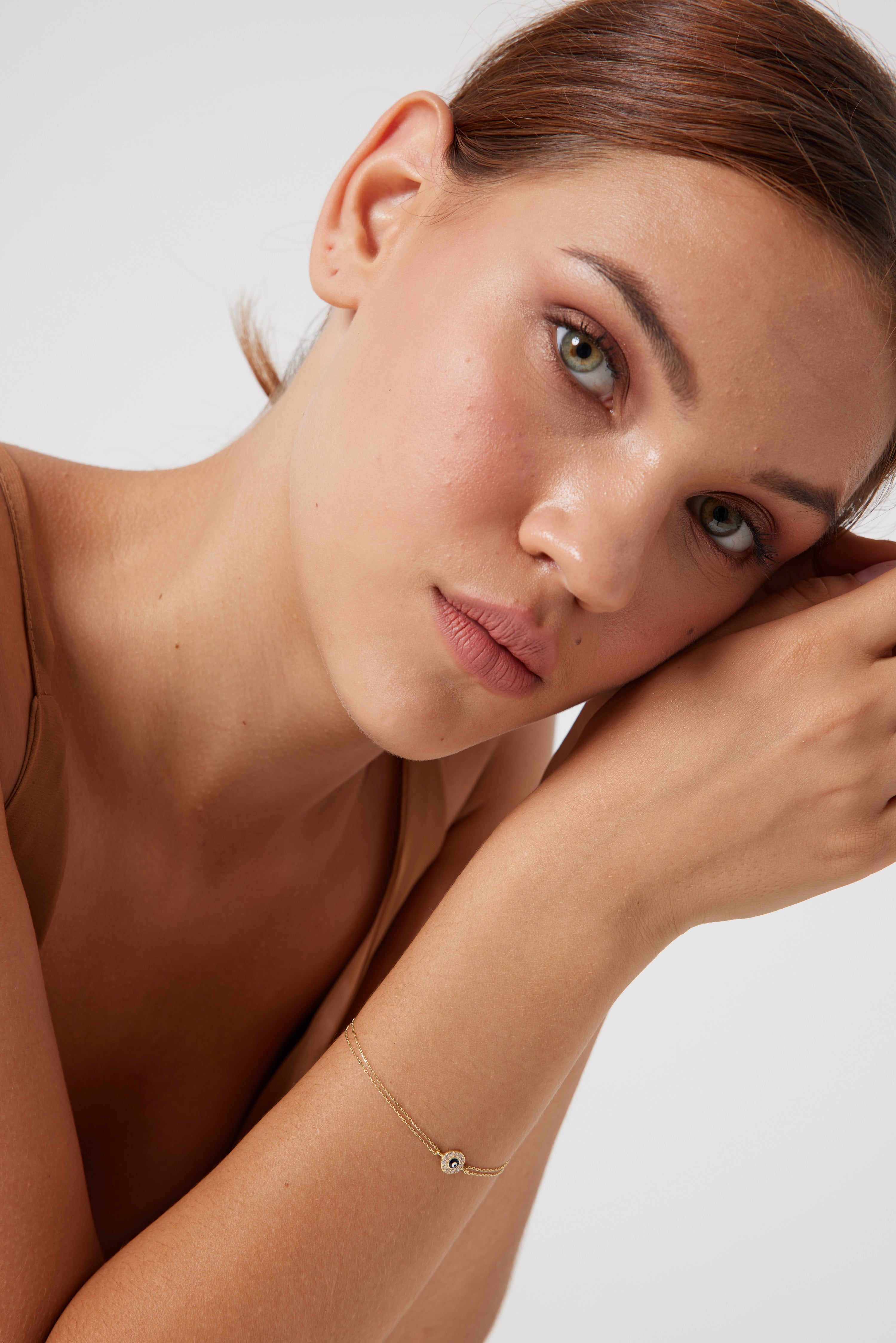 Model wearing a delicate 14K solid yellow gold round evil eye bracelet, showcasing its minimalist design and elegance.