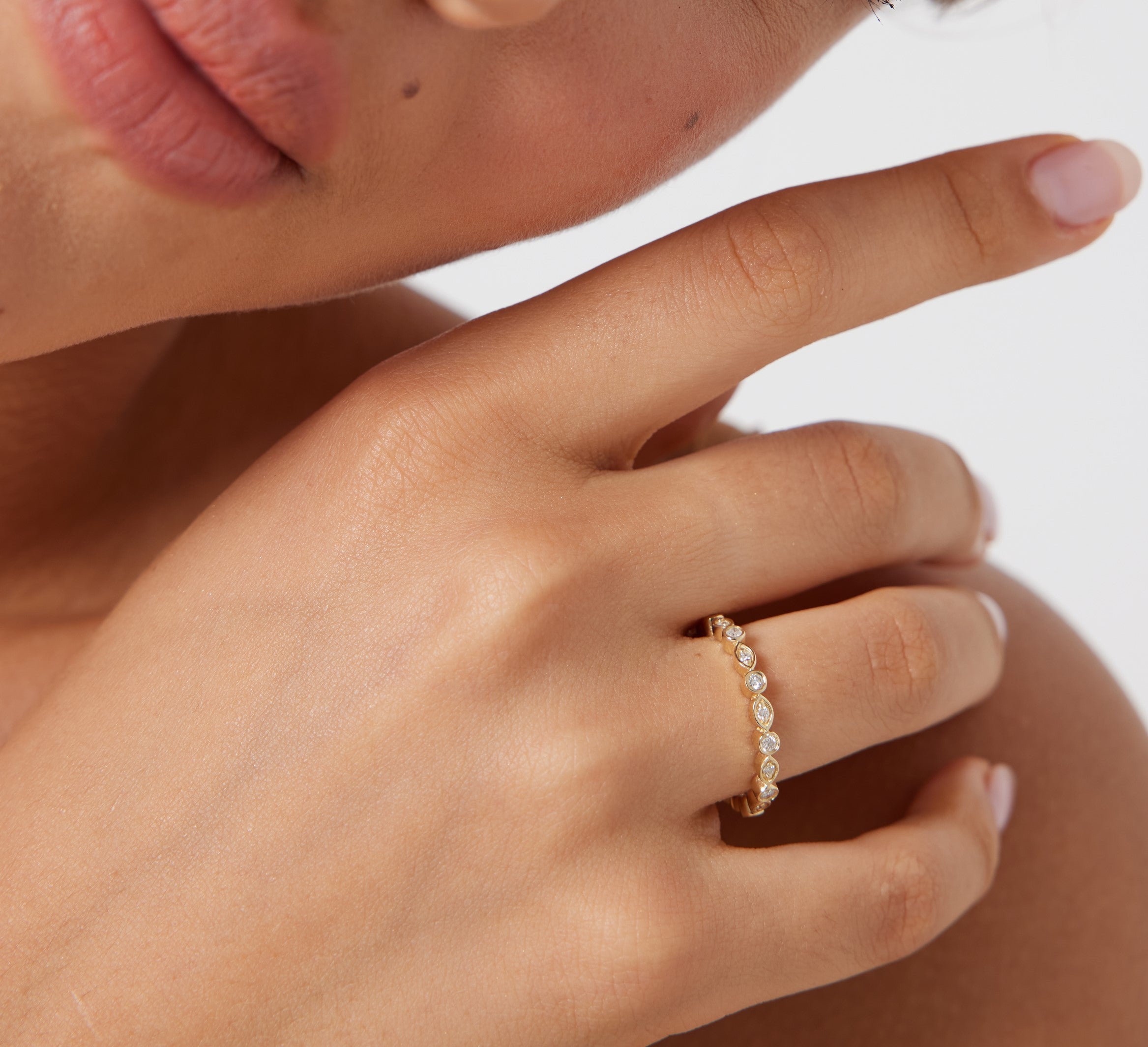 Close-up of a woman wearing a 14K gold women’s full eternity diamond wedding ring with round diamonds.