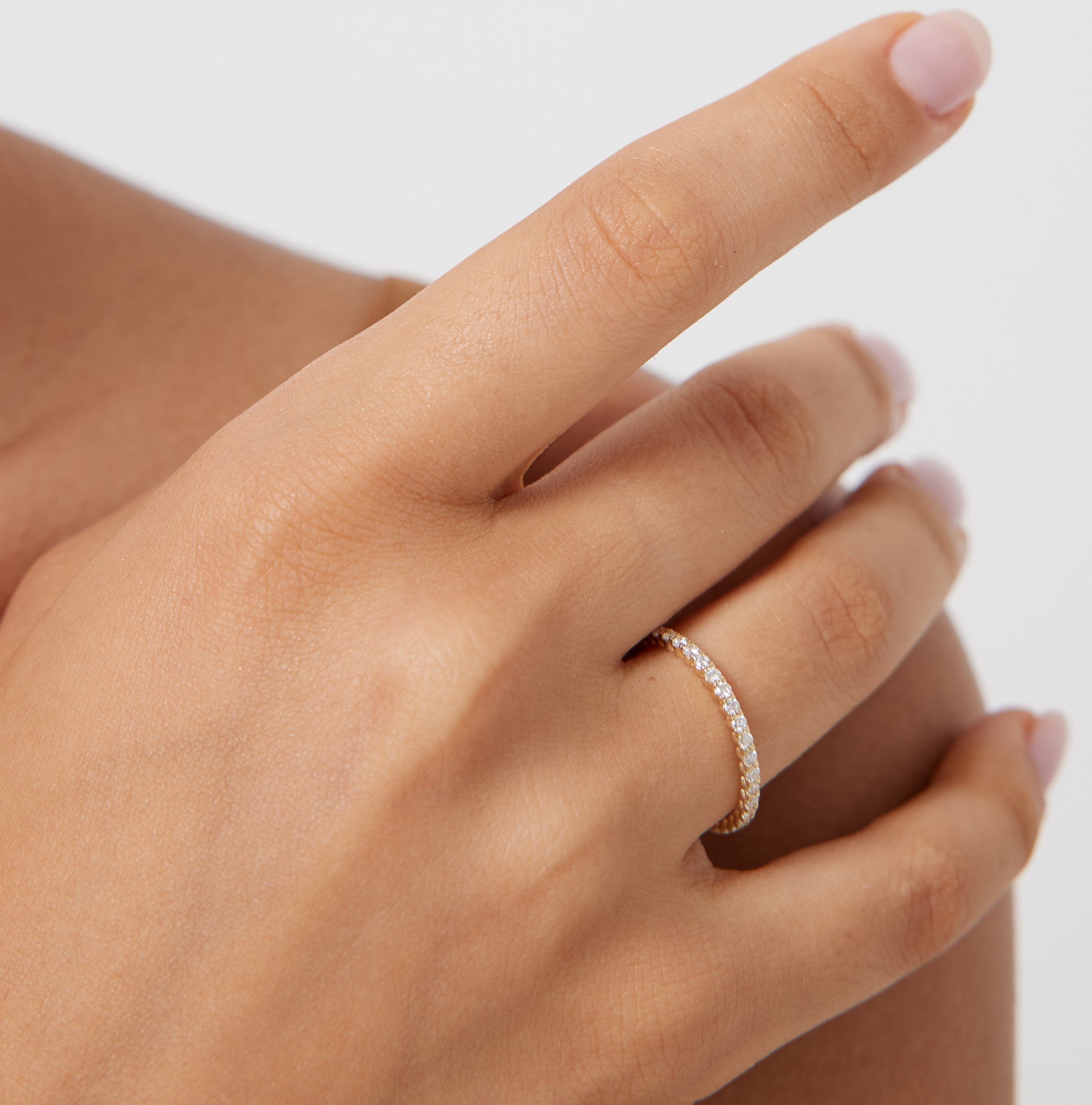 14K gold full eternity diamond ring on hand featuring 37 round diamonds, 0.60 carats, shiny finish.